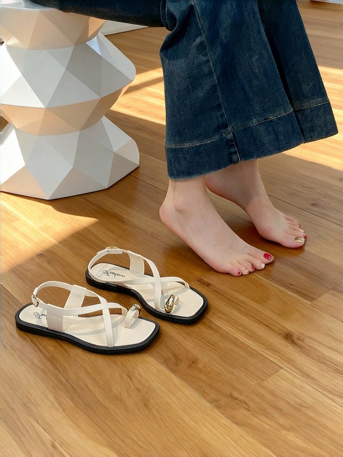 Women's white flat slide sandals featuring criss cross straps, shell detail, and buckle accents