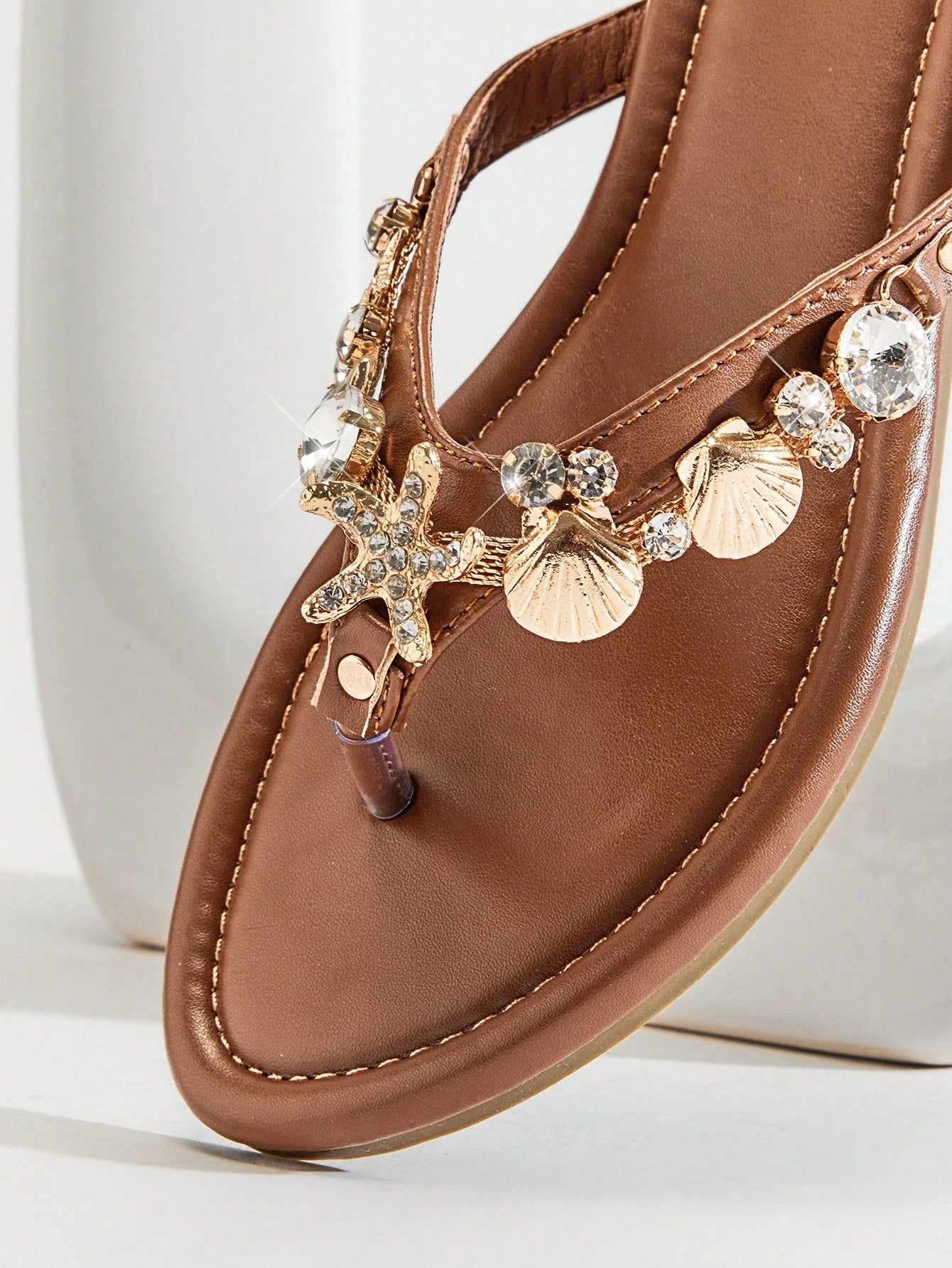 Women's flat toe post thong sandals with sea shell and starfish decoration, slide-style design, PU leather upper and TPR outsole.