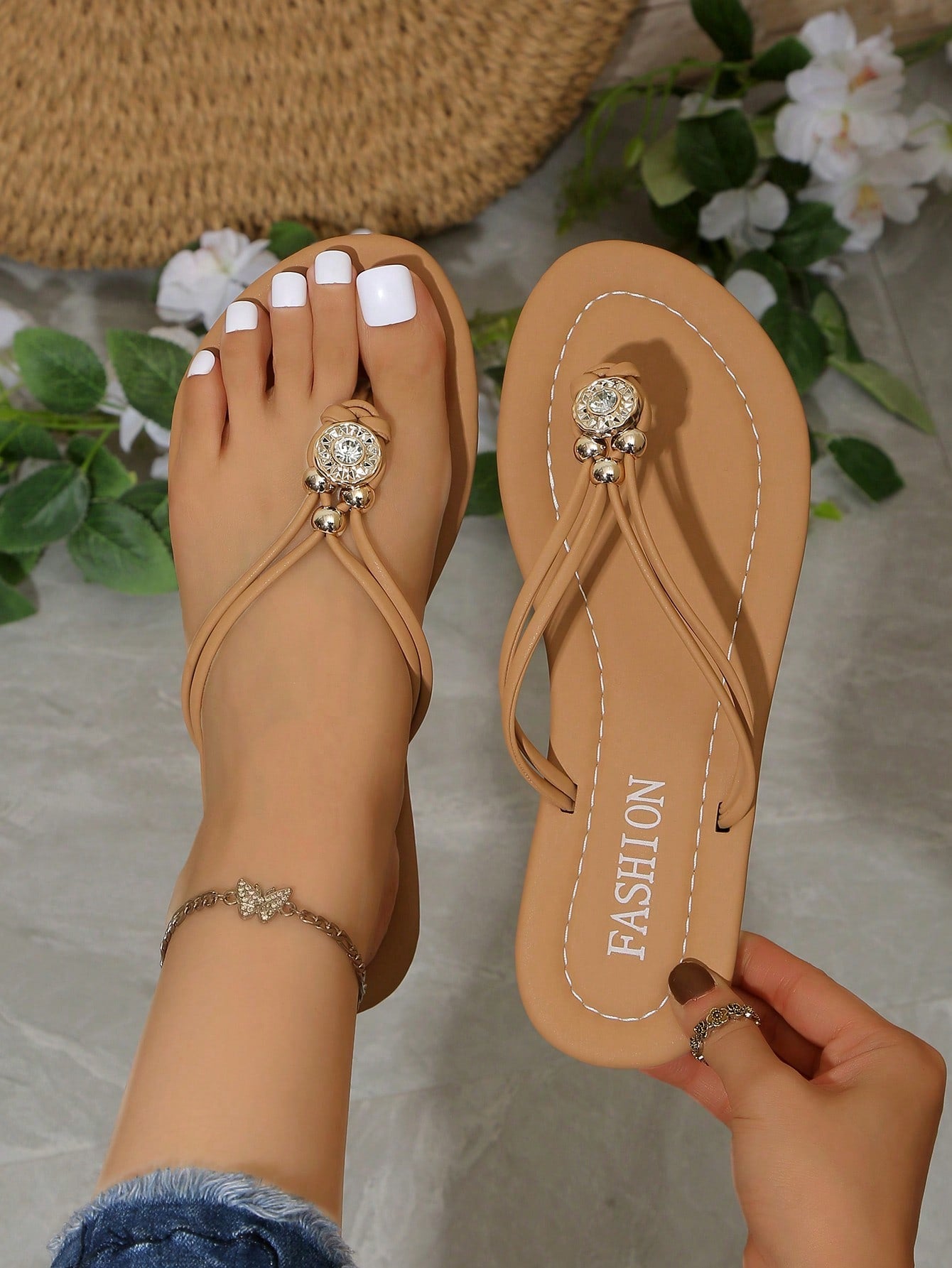 Women's brown thong flat sandals with toe post, rhinestone embellishments, beaded rope details, and metal buckle accent in a slip-on flip flop style.