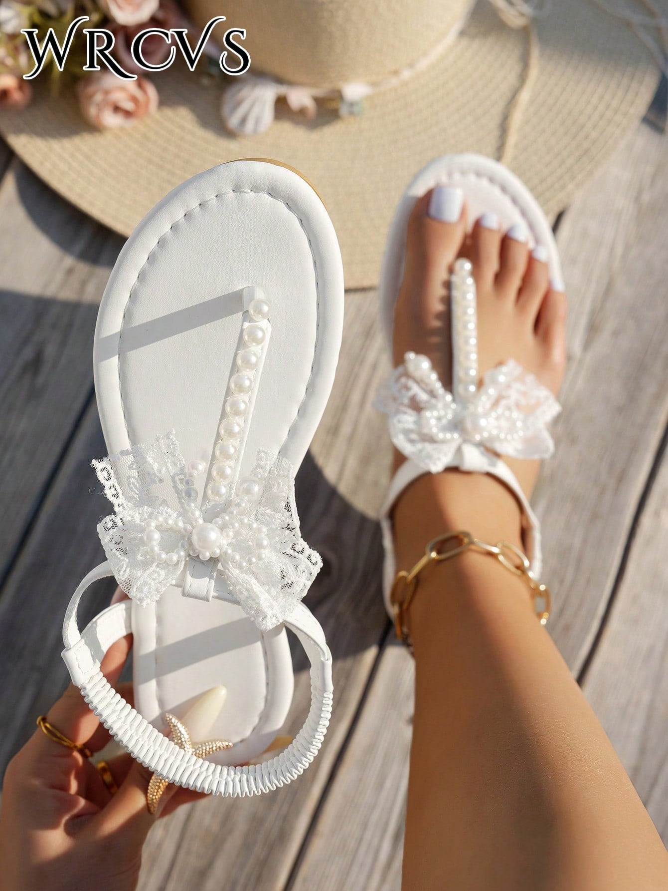 Beige women's flat thong Roman-style sandals with toe post, rhinestone and bow decoration, and buckle detail.