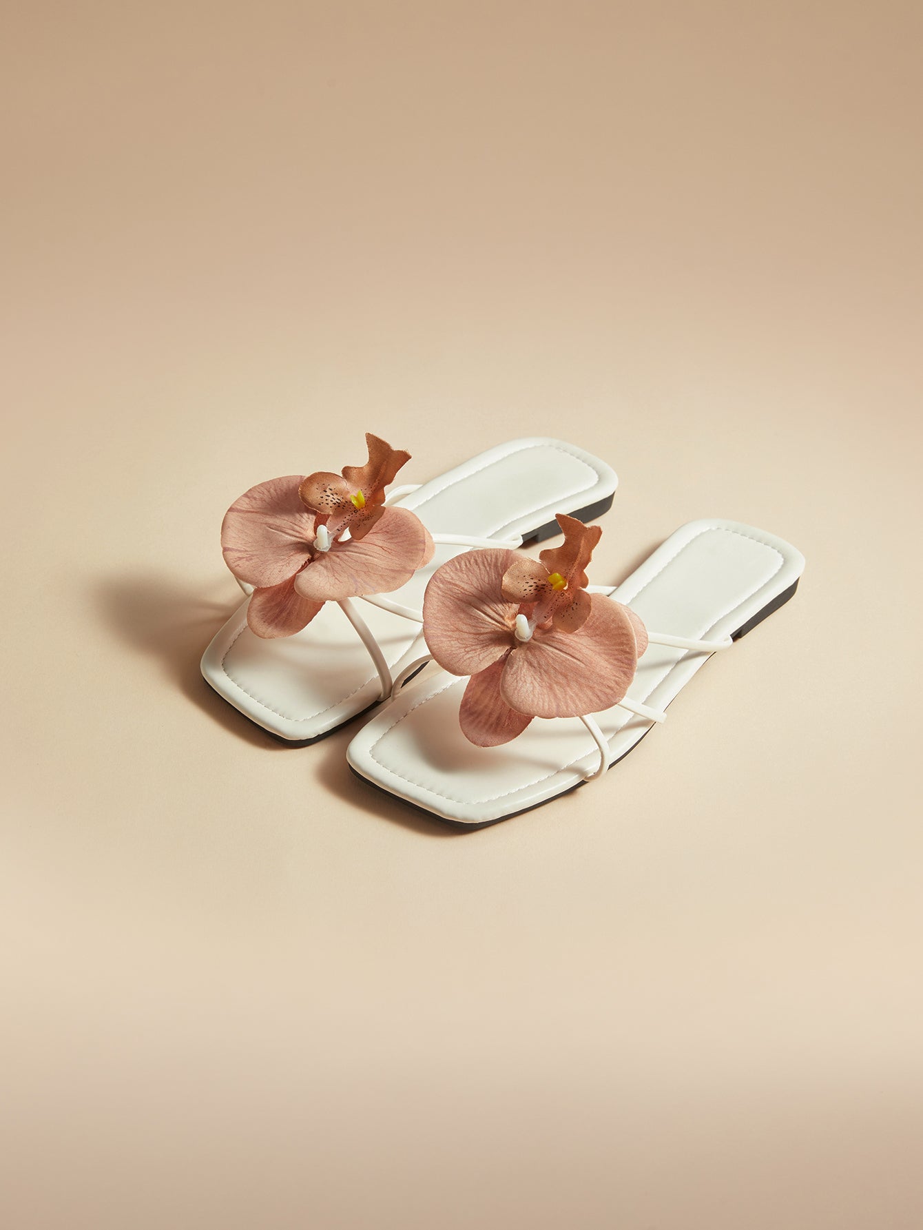 Brown women's flat slide sandals with floral applique strap and plant-inspired design, suitable for outdoor summer wear.