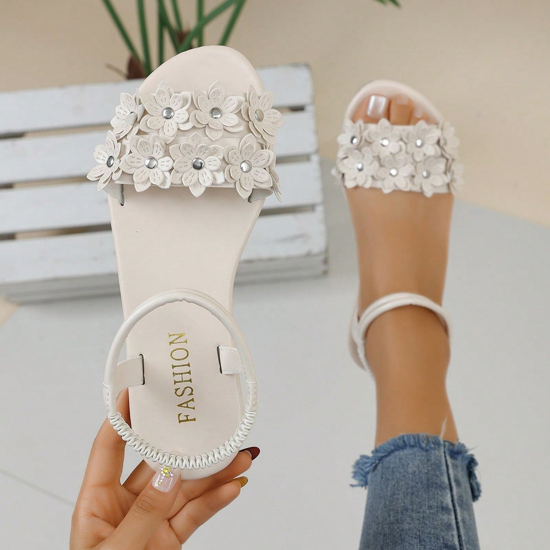 Women's beige flat sandals with stitched flower petal detail, open toe front, and adjustable ankle strap for casual warm-weather and beach wear.