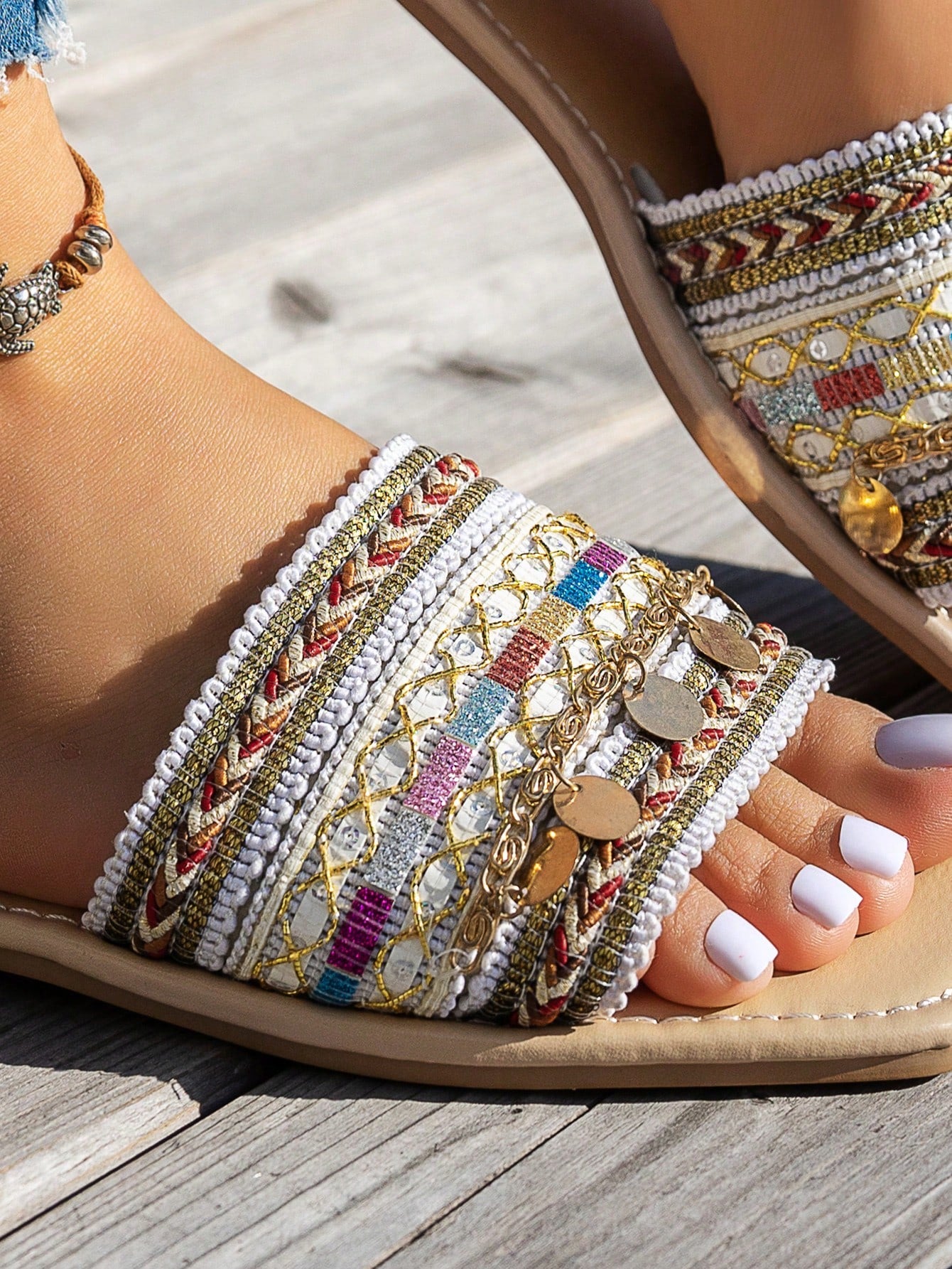 Pair of green women’s flat slide sandals with open toes, embroidered and beaded detailing, and fringe accents in a vacation style.