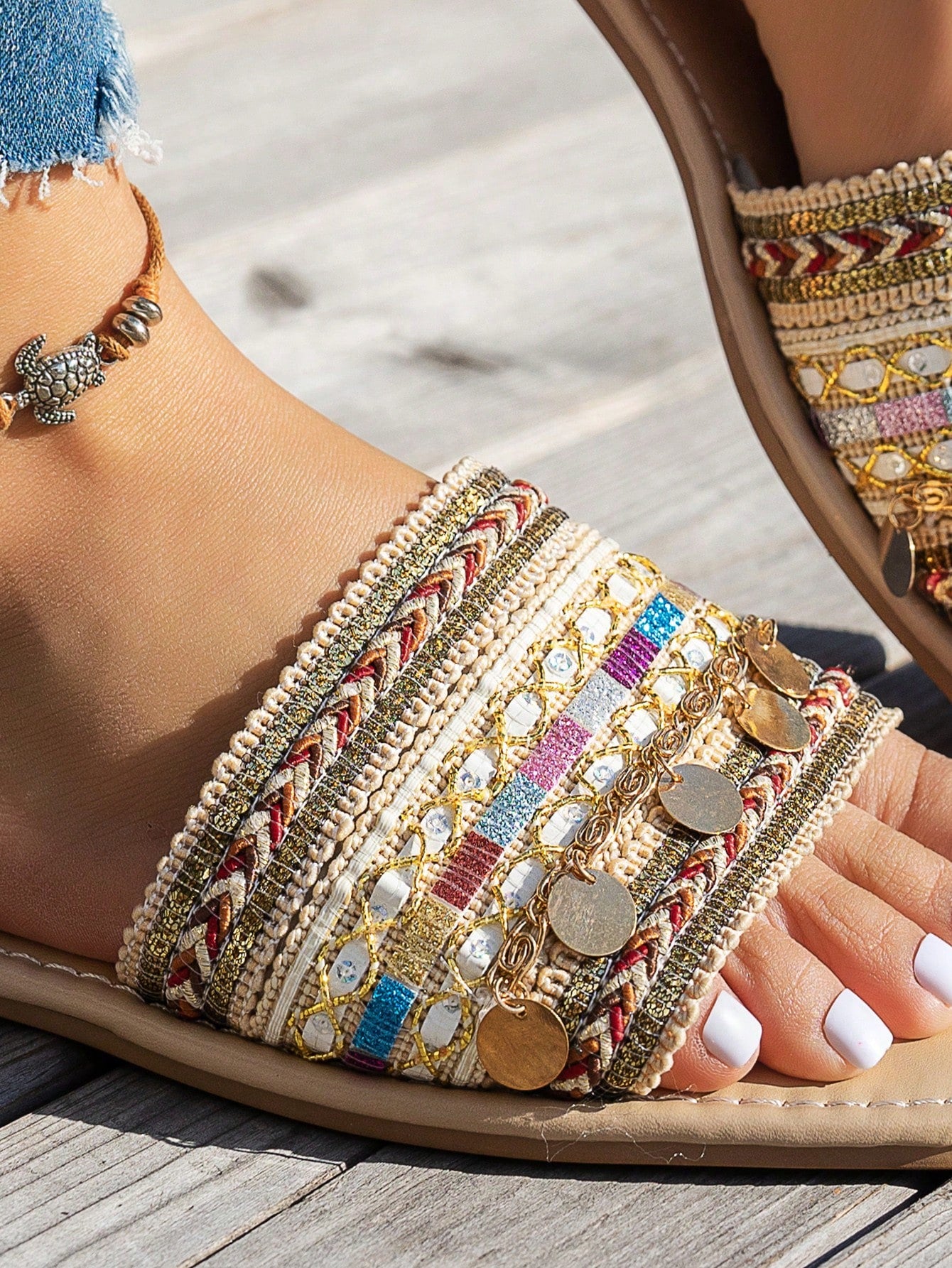 Pair of green women’s flat slide sandals with open toes, embroidered and beaded detailing, and fringe accents in a vacation style.