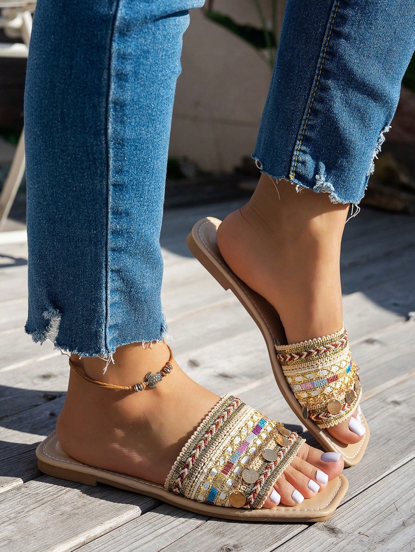 Pair of green women’s flat slide sandals with open toes, embroidered and beaded detailing, and fringe accents in a vacation style.