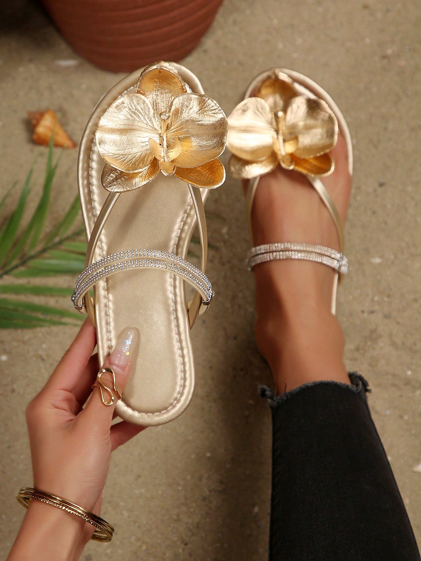 Women's flat slide sandals with open toe, floral applique detail, and criss-cross straps, shown as casual vacation-style summer footwear.