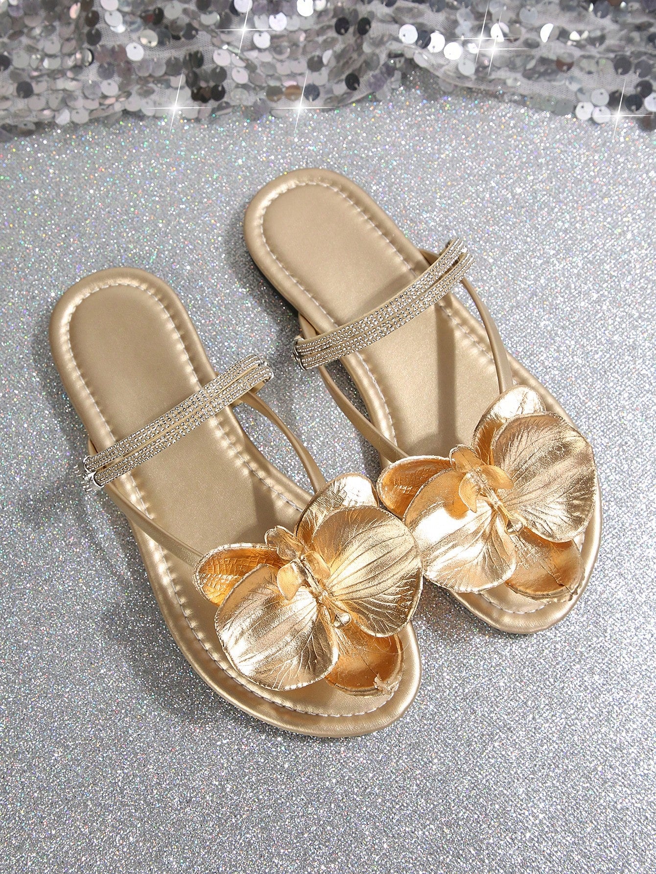 Women's flat slide sandals with open toe, floral applique detail, and criss-cross straps, shown as casual vacation-style summer footwear.