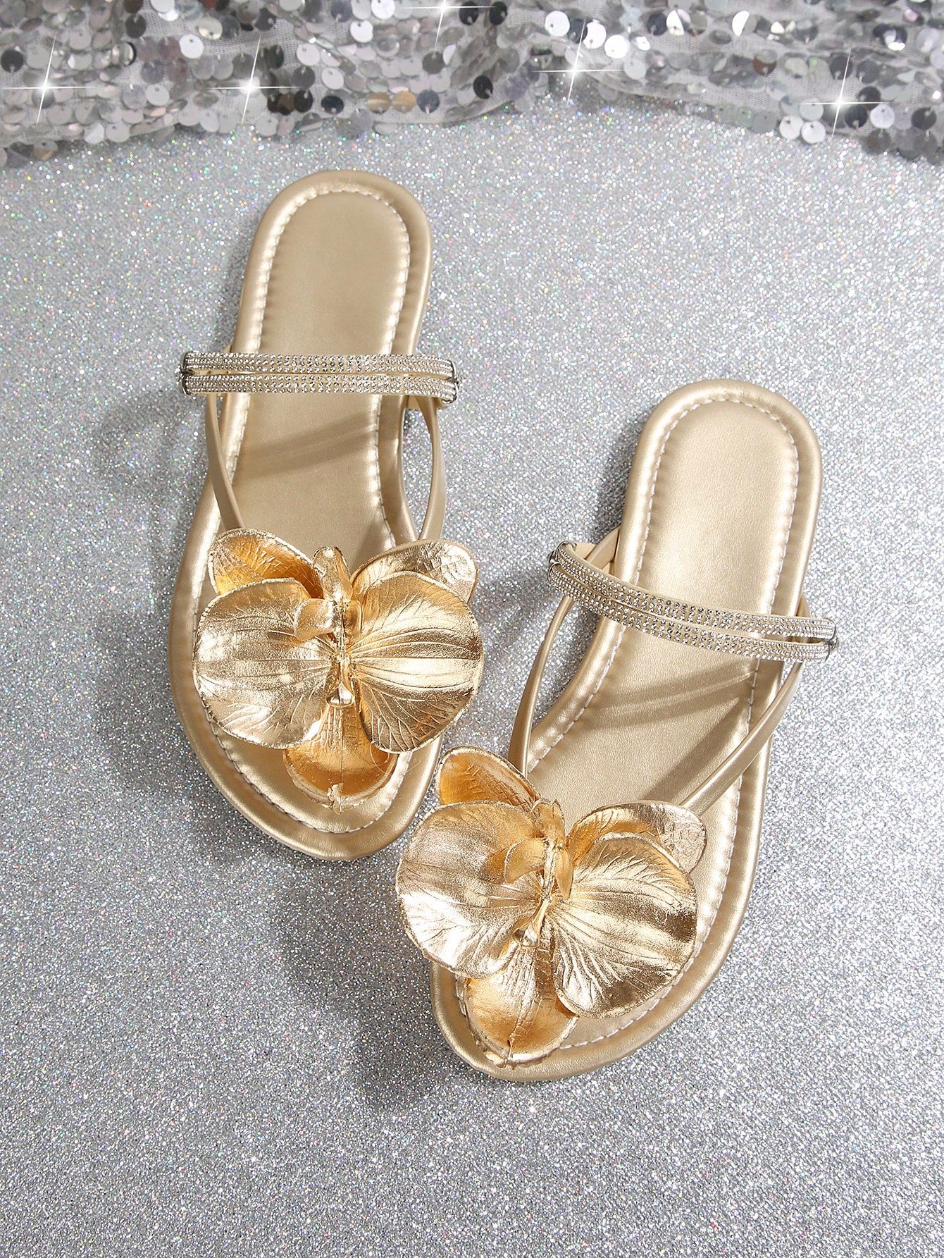 Women's flat slide sandals with open toe, floral applique detail, and criss-cross straps, shown as casual vacation-style summer footwear.