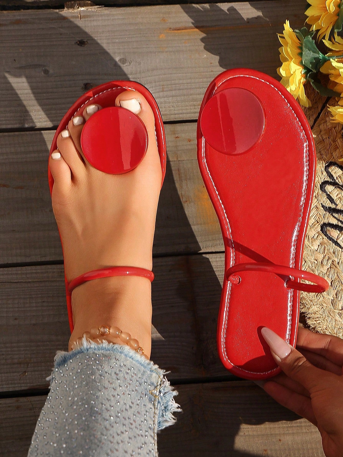 Women’s flat thong sandals with a shiny round buckle, high-gloss finish, semi-circle strap, and toe post design