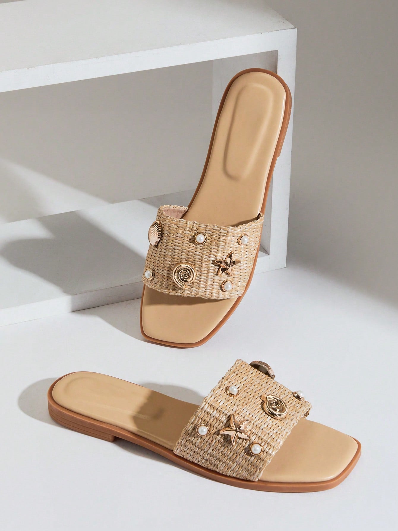 Women's slip-on flat slide sandals with open toe, woven one-band upper, and seashell and pearl ornaments in a marine life-inspired design.