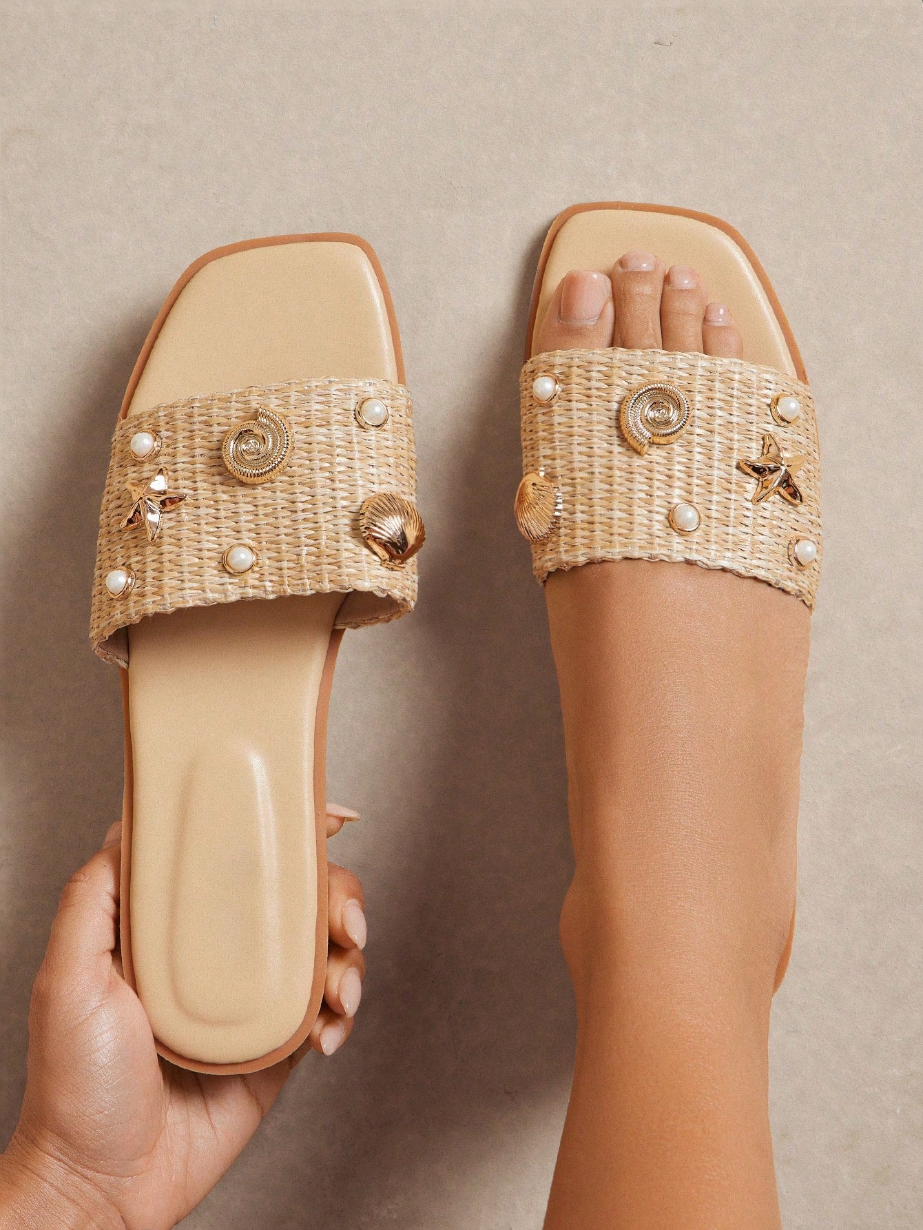 Women's slip-on flat slide sandals with open toe, woven one-band upper, and seashell and pearl ornaments in a marine life-inspired design.