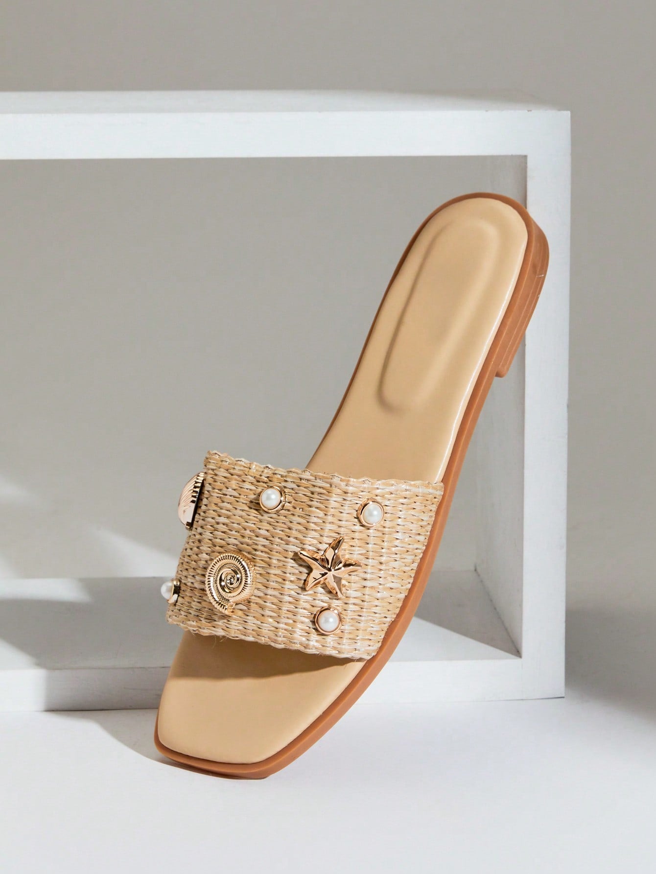 Women's slip-on flat slide sandals with open toe, woven one-band upper, and seashell and pearl ornaments in a marine life-inspired design.