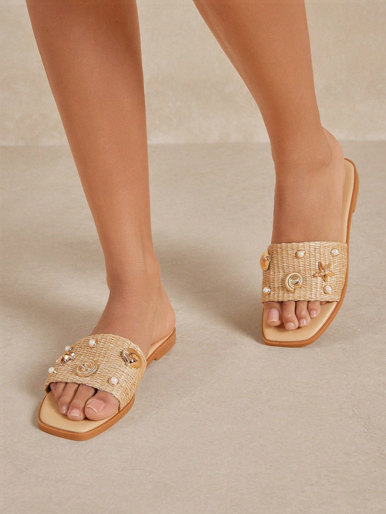 Women's slip-on flat slide sandals with open toe, woven one-band upper, and seashell and pearl ornaments in a marine life-inspired design.