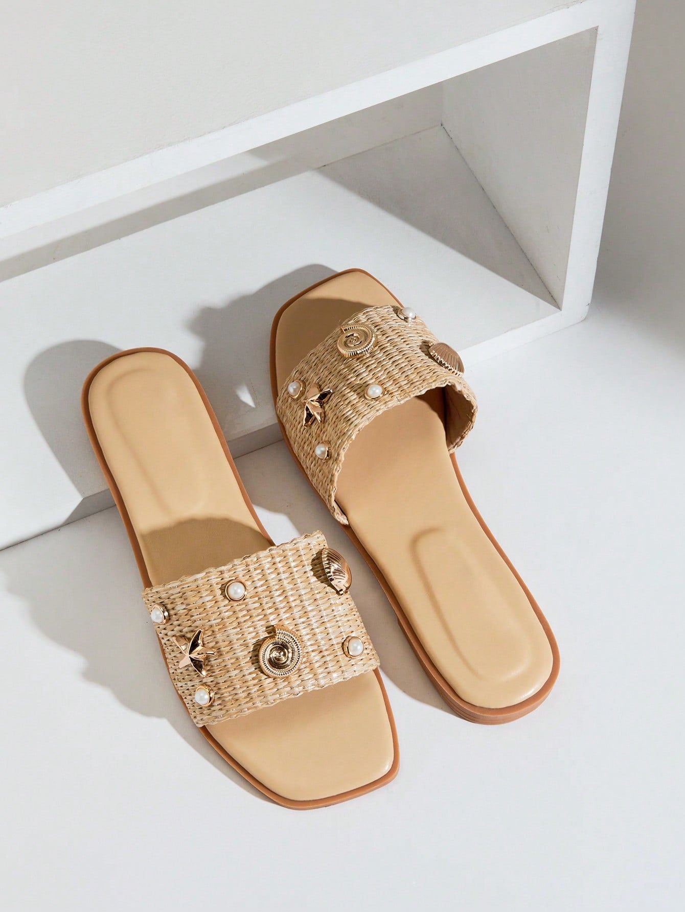 Women's slip-on flat slide sandals with open toe, woven one-band upper, and seashell and pearl ornaments in a marine life-inspired design.