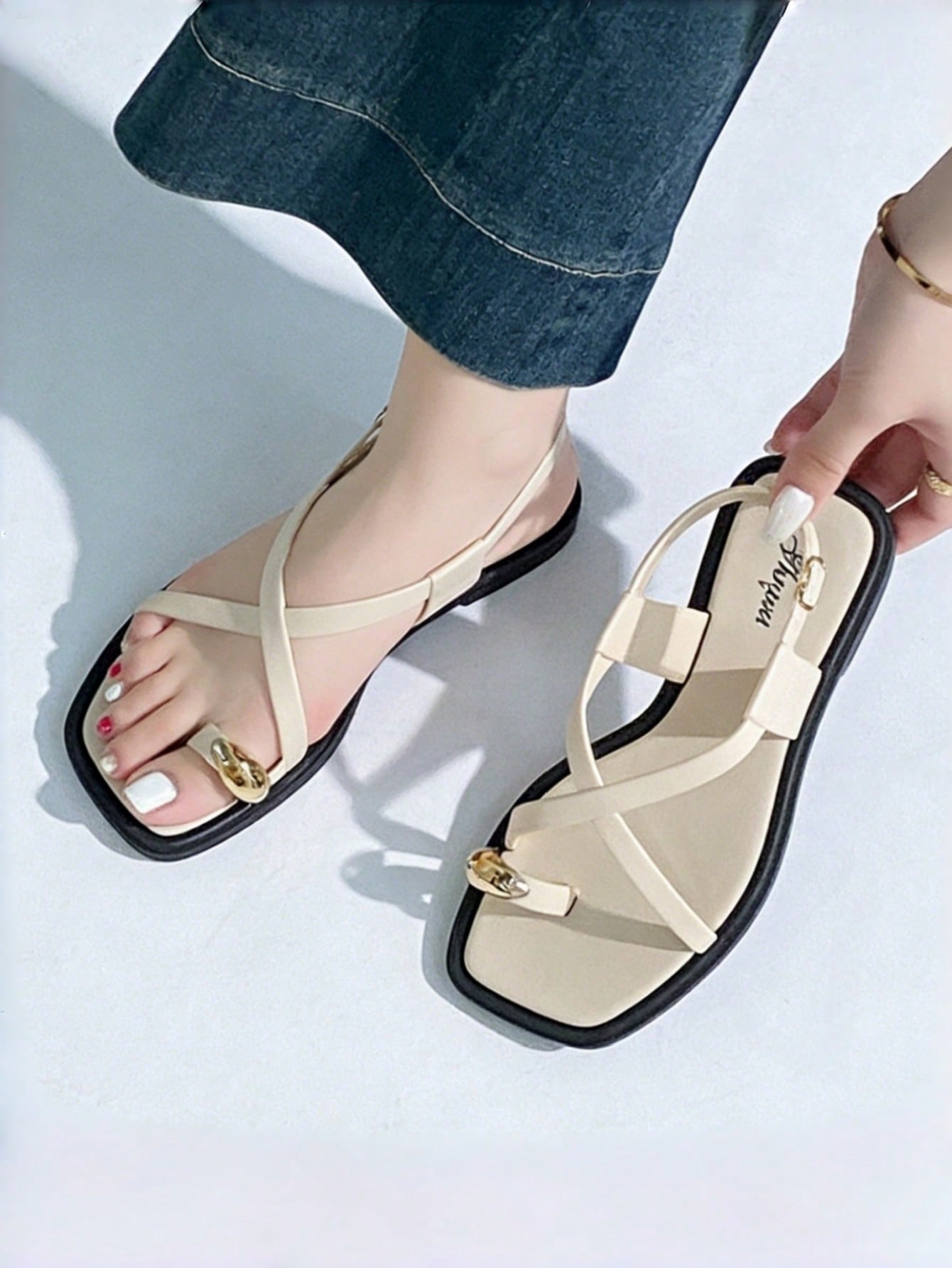 Women's white flat slide sandals featuring criss cross straps, shell detail, and buckle accents