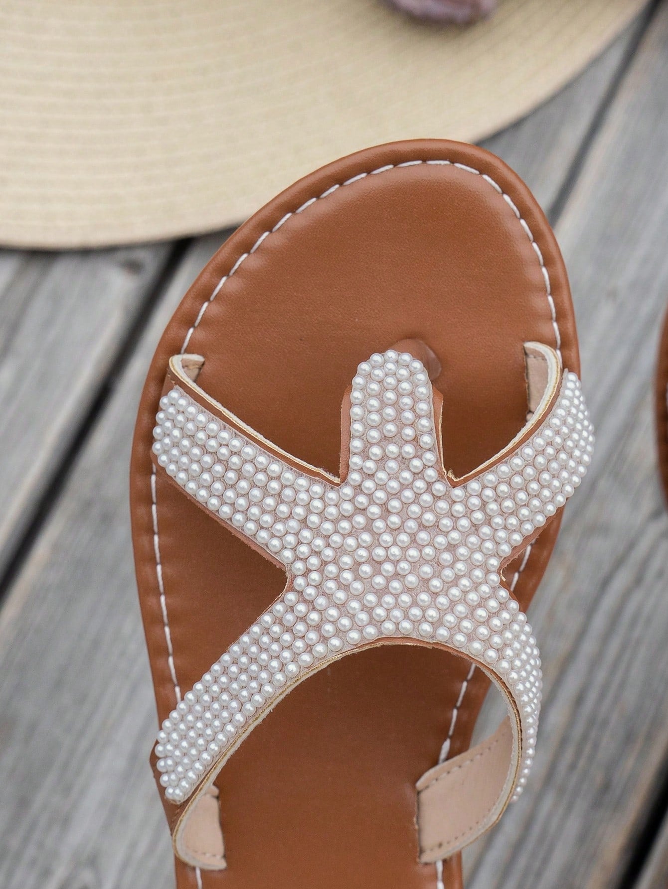 Women's brown flat thong sandals with starfish and pearl detail, criss-cross straps, and toe post design for beach casual summer wear.