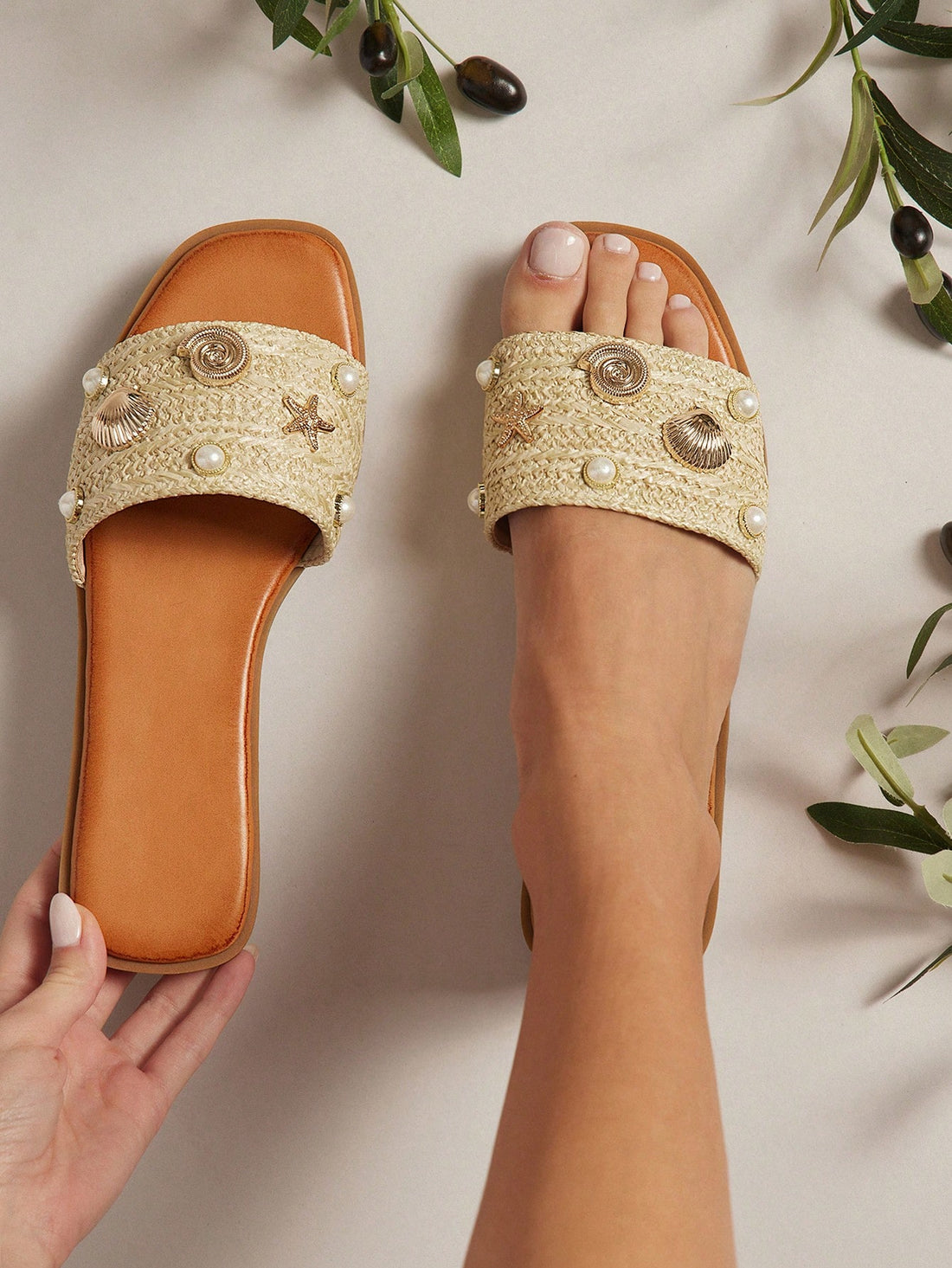 Women's slip-on flat slide sandals with open toe, woven one-band upper, and seashell and pearl ornaments in a marine life-inspired design.