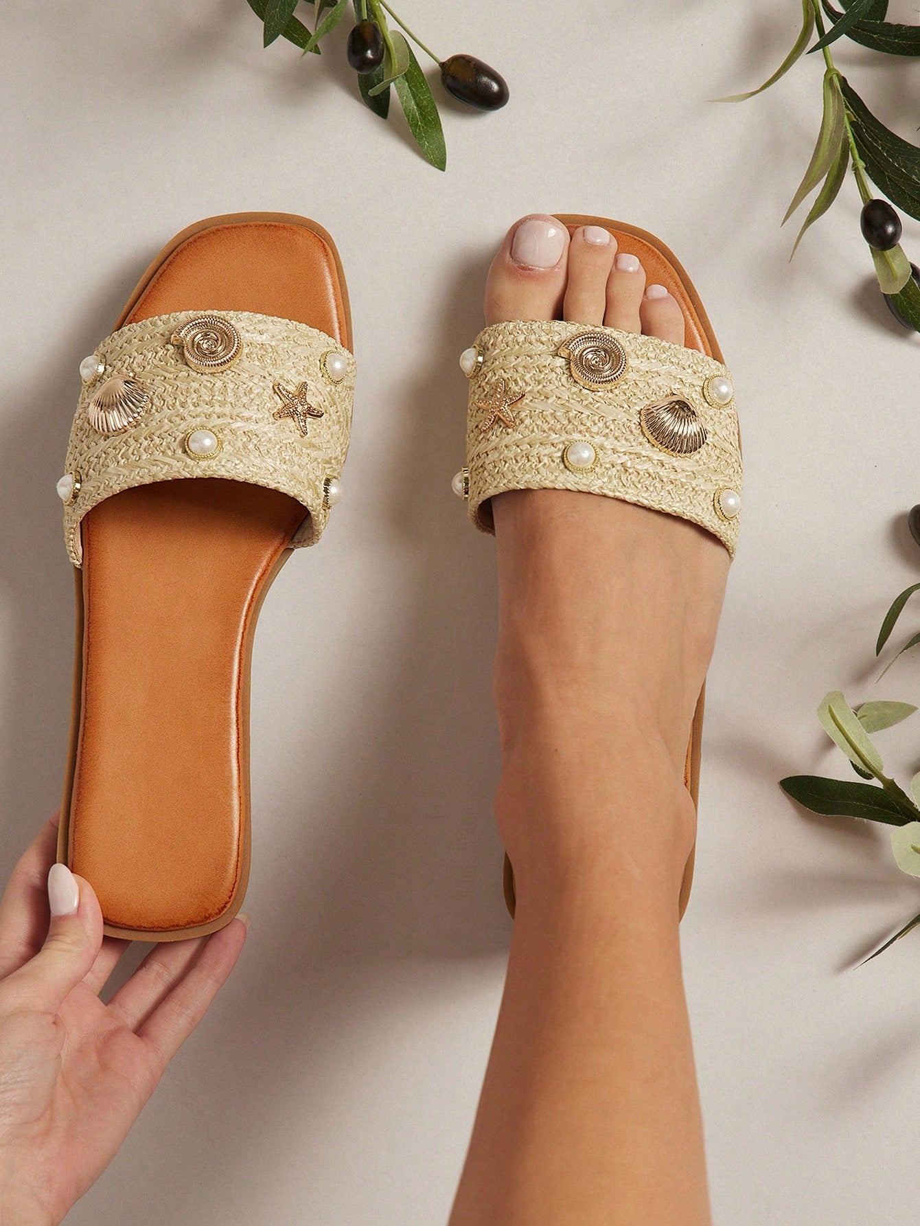Women's slip-on flat slide sandals with open toe, woven one-band upper, and seashell and pearl ornaments in a marine life-inspired design.