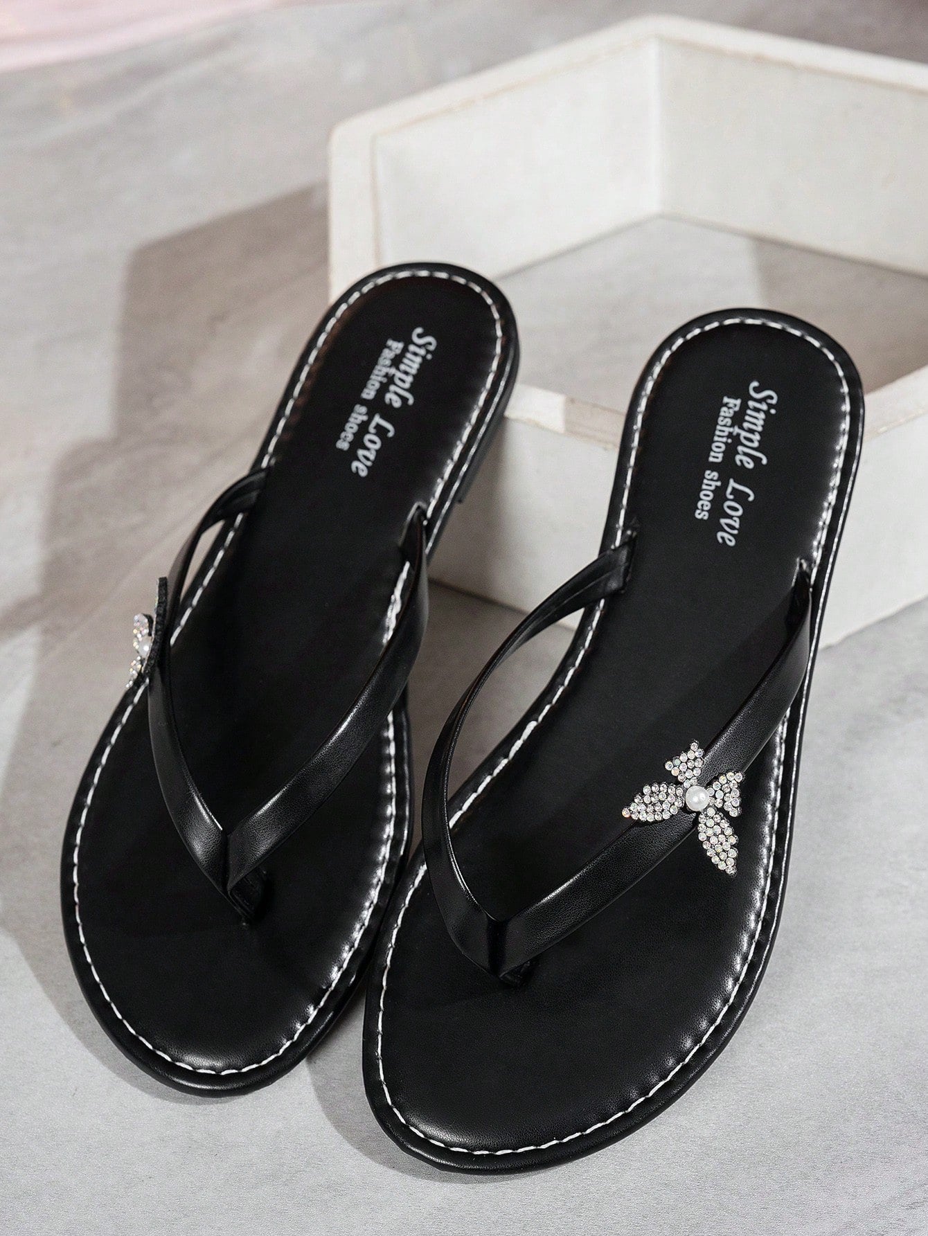 Women's black flip flop sandals with butterfly and flower pearl crystal embellishments, round toe, flat sole, and minimalist summer beach style.