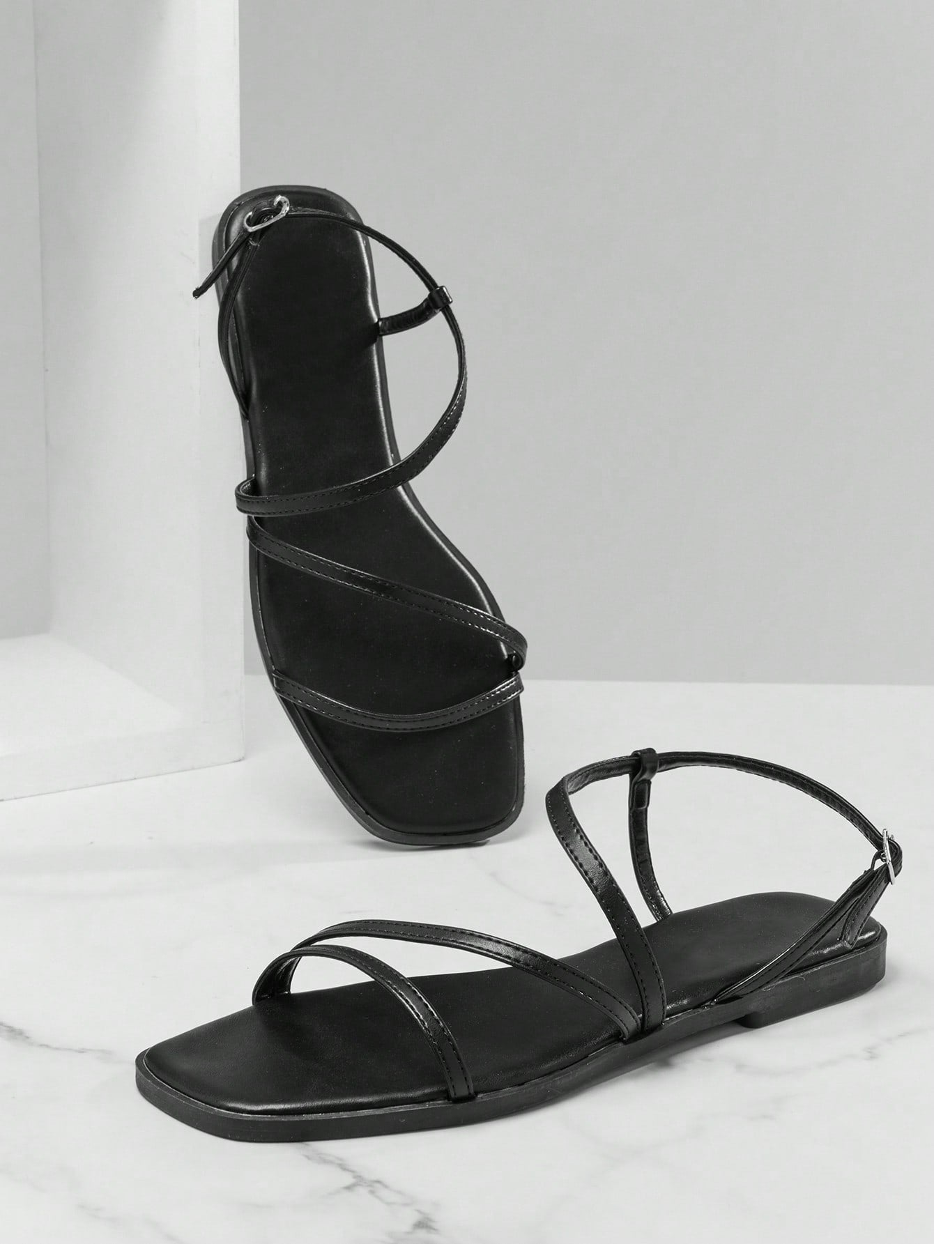 Women's flat open-toe sandals featuring a buckle detail and PU leather construction with a flat sole.