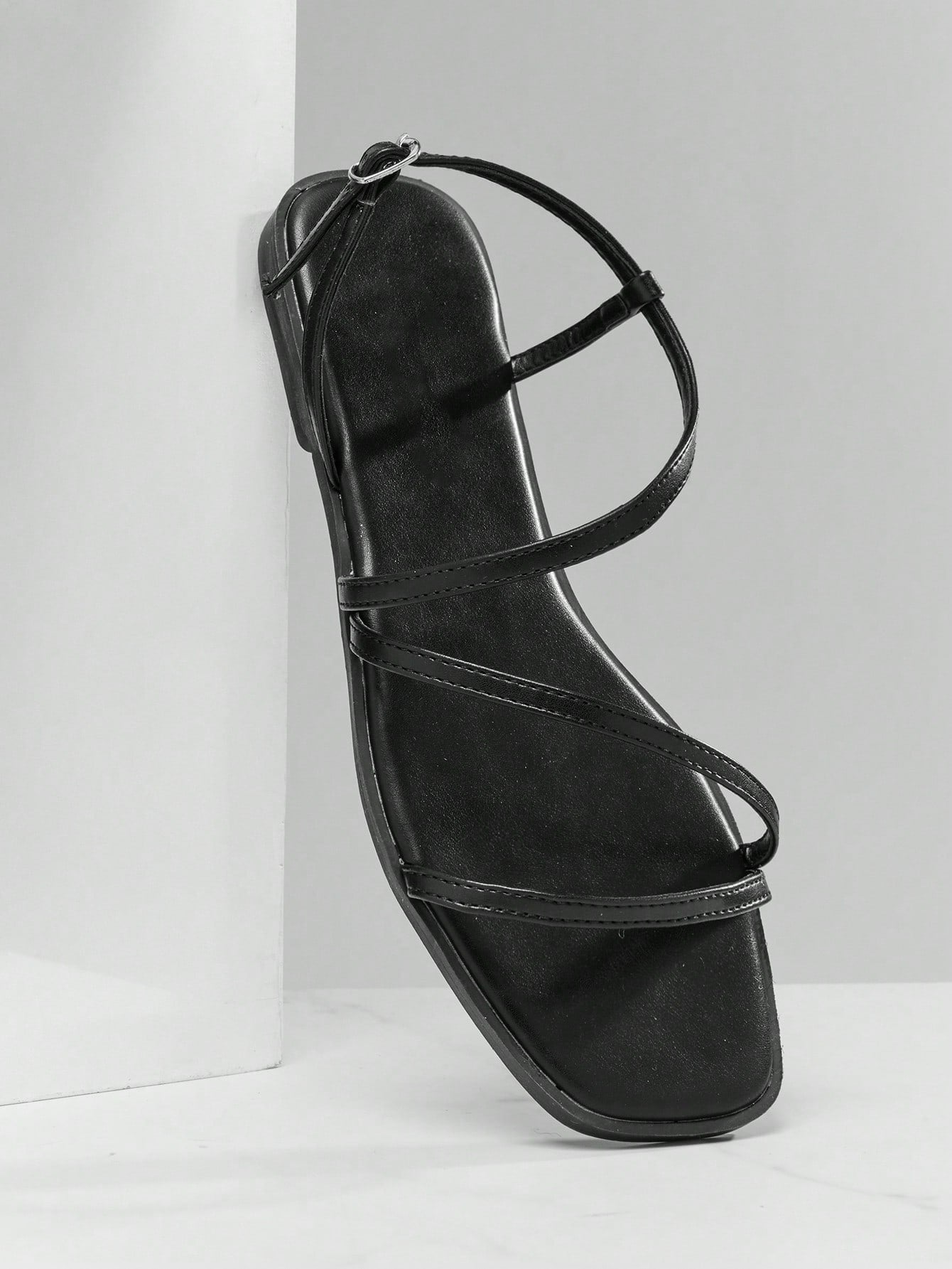 Women's flat open-toe sandals featuring a buckle detail and PU leather construction with a flat sole.