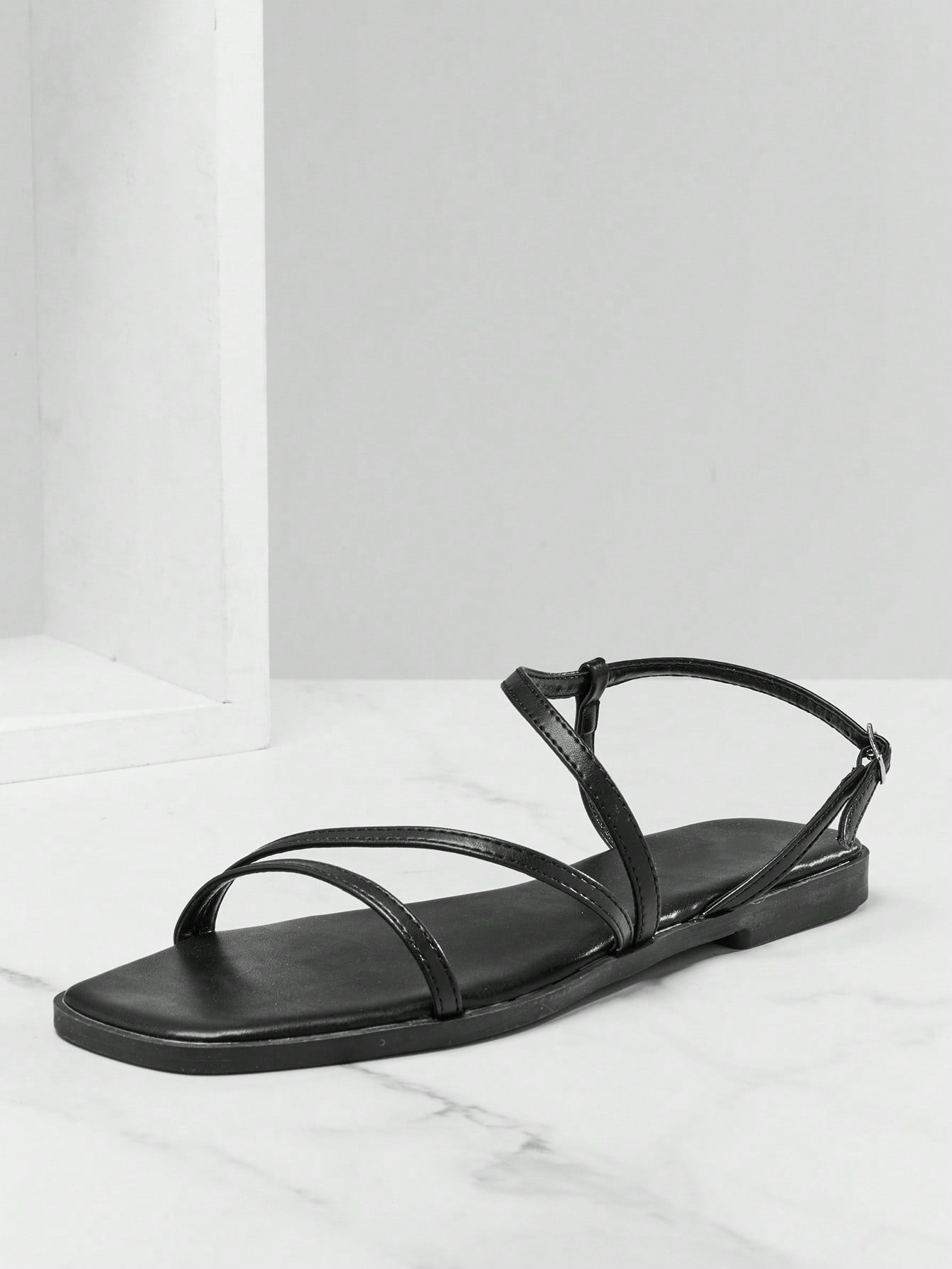 Women's flat open-toe sandals featuring a buckle detail and PU leather construction with a flat sole.