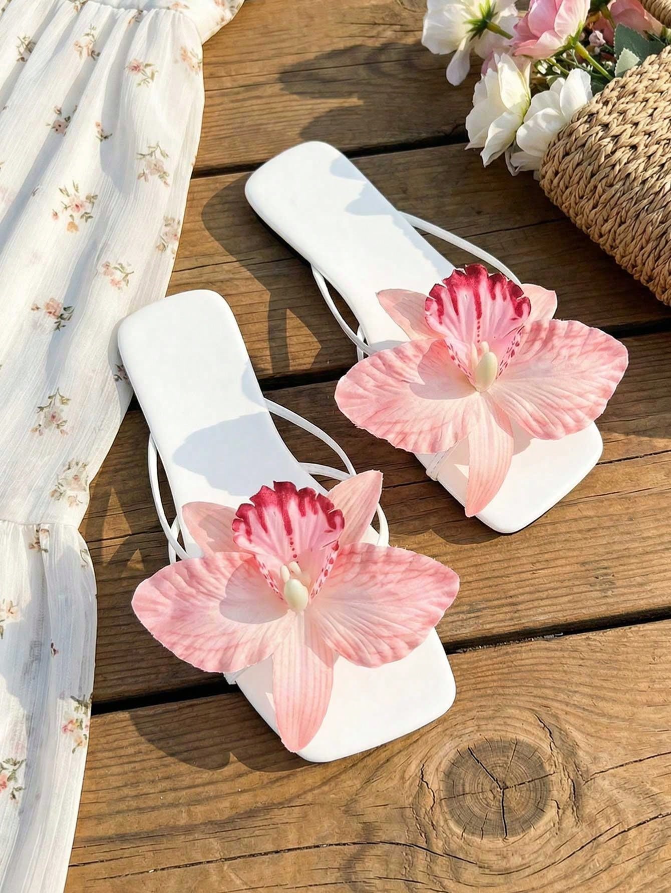 Women's flat woven slide sandals with open toe, featuring 3D flower and pearl appliques in an apricot and blue flower colorway, shown as casual vacation beach slippers.