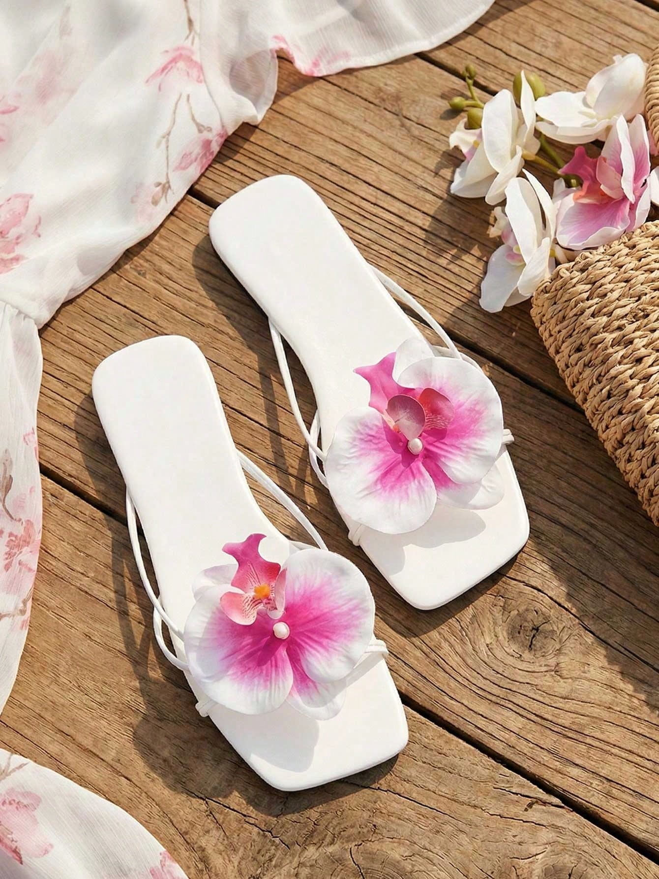 Women's flat woven slide sandals with open toe, featuring 3D flower and pearl appliques in an apricot and blue flower colorway, shown as casual vacation beach slippers.