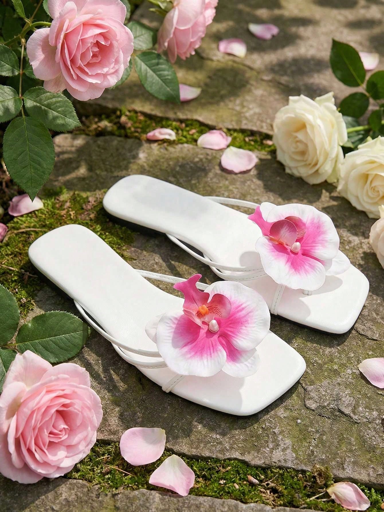 Women's white open-toe slide flat sandals with pink flower applique on the strap