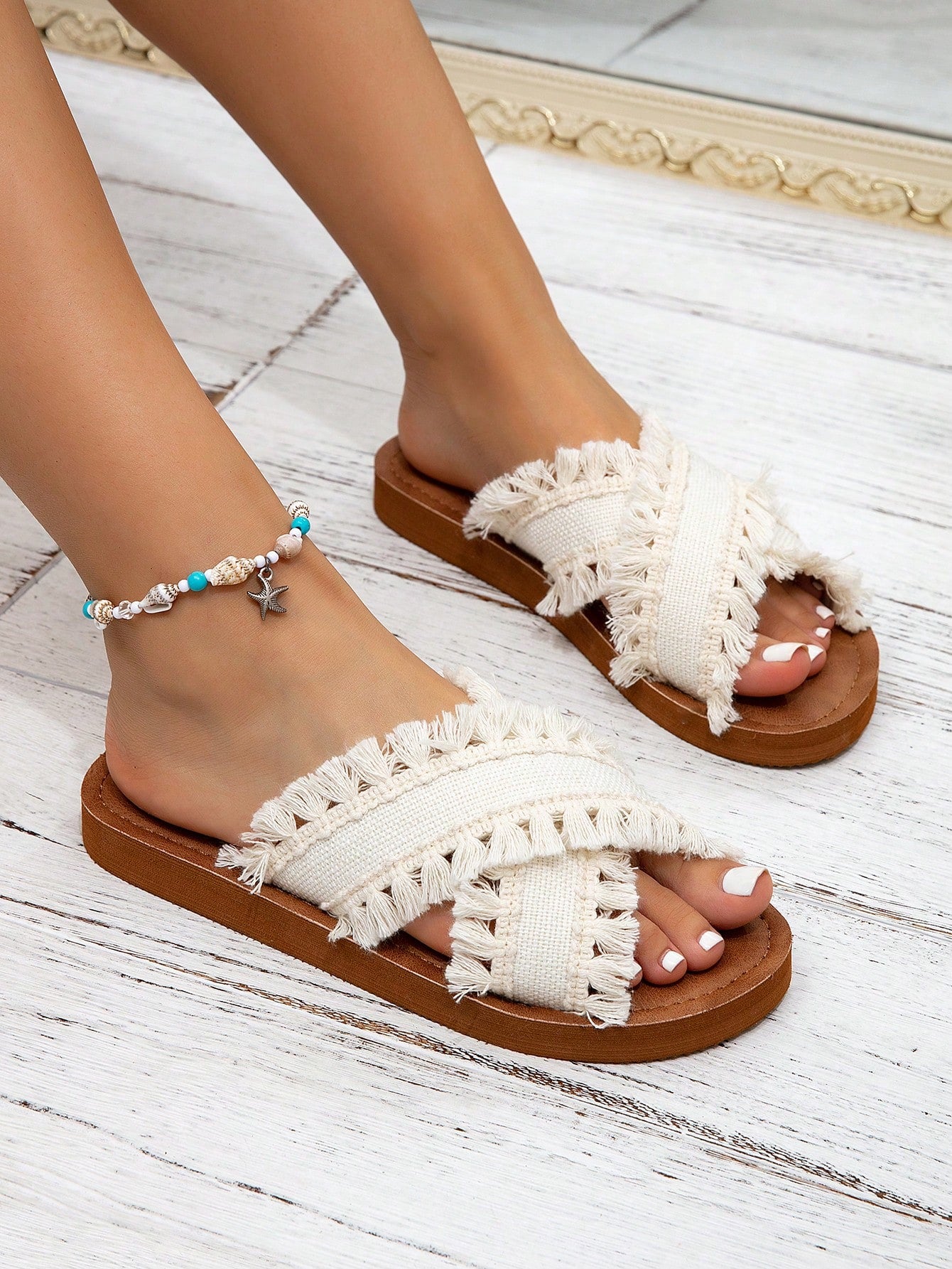 Women's flat slide sandals with ruched fabric, bow accent, and fringe detail, suitable for outdoor vacation wear.