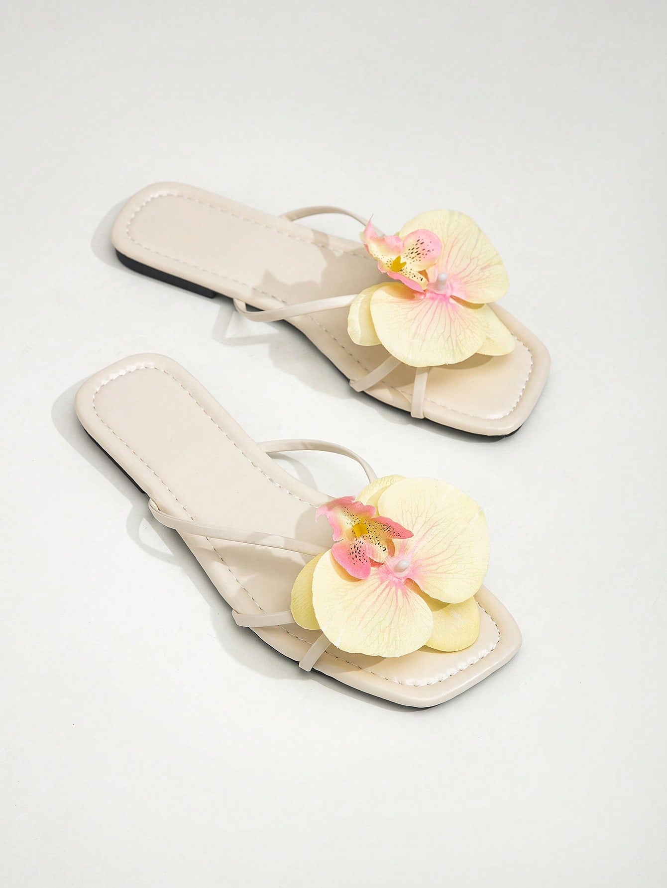Wide fit women's beige flat thong sandals with butterfly orchid appliqué decor and open toe, suitable for beach, vacation, home, and casual everyday wear.