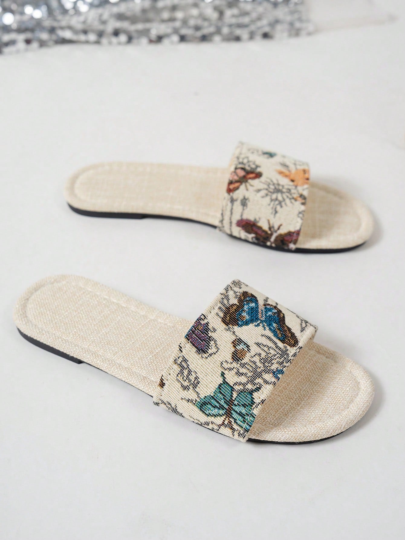 Women’s flat slide sandals featuring a floral printed strap and open toe design in a minimal style.