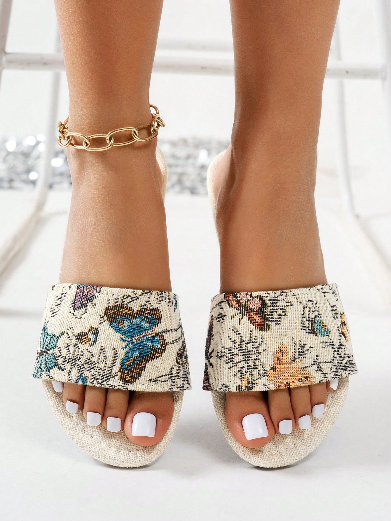 Women’s flat slide sandals featuring a floral printed strap and open toe design in a minimal style.