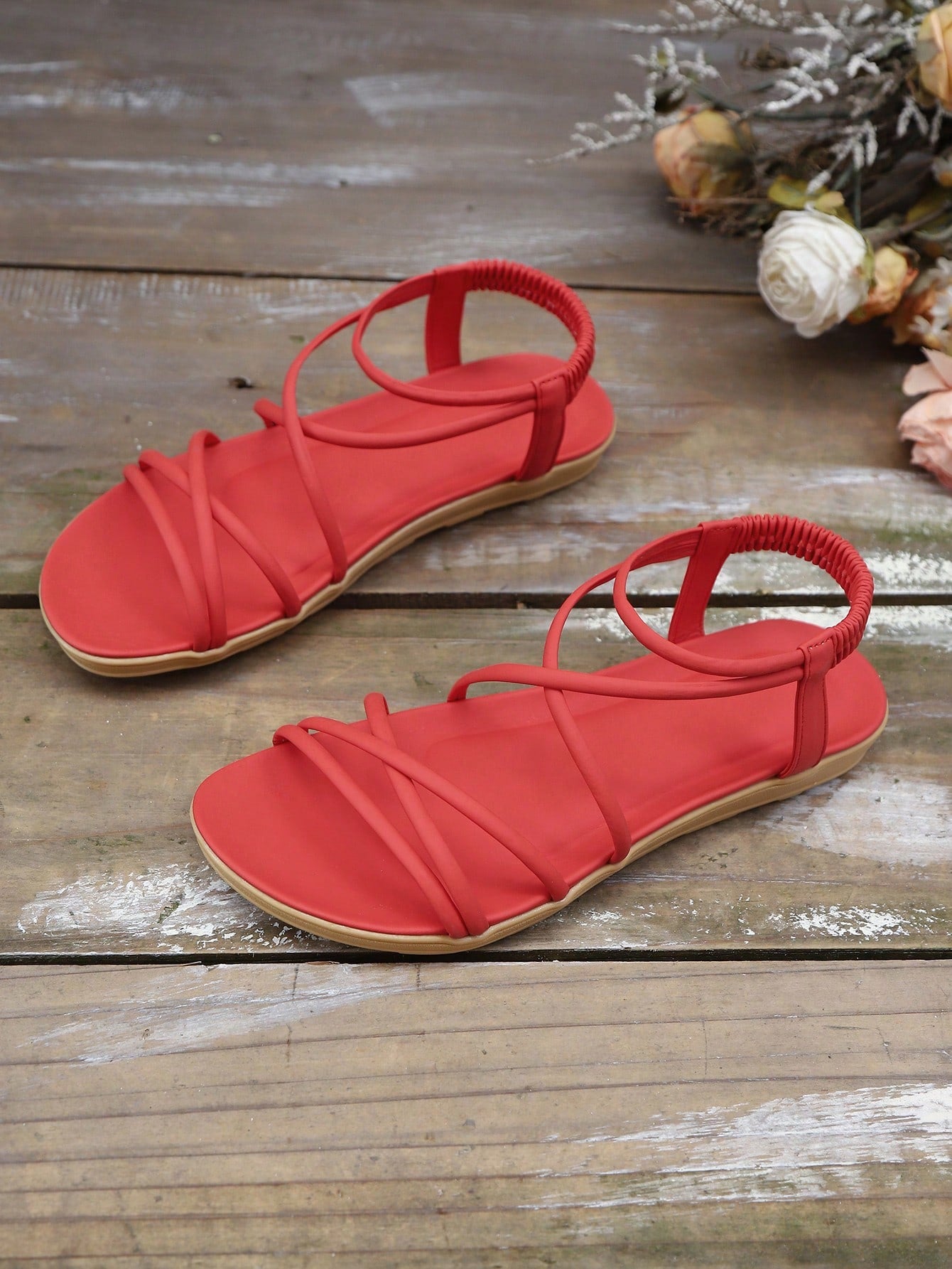 Women's beige flat sandals with criss cross straps, ankle strap, and open toe.