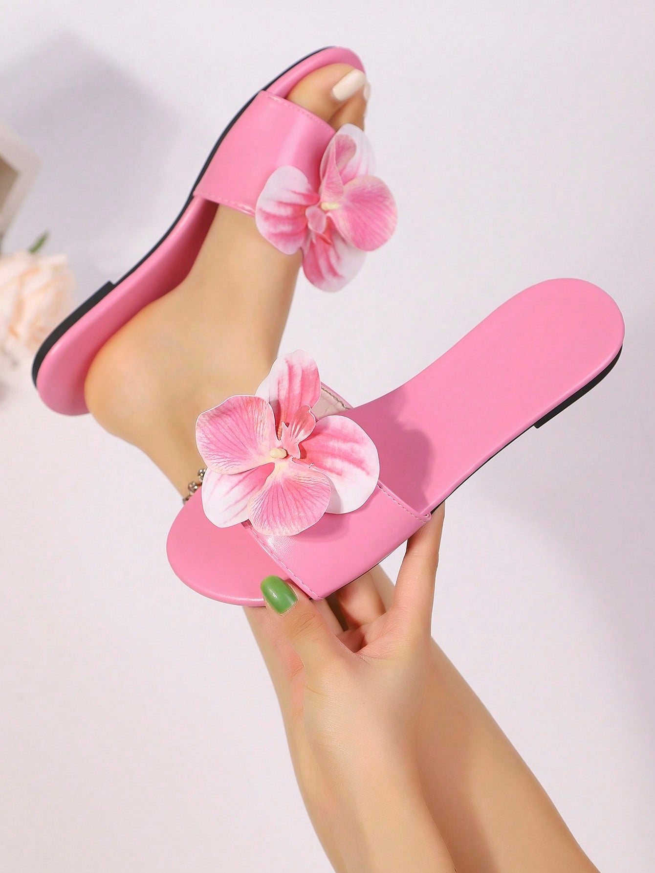 Women’s open toe flat toe-ring slide sandals with artificial flower applique detail and vacation beach style.