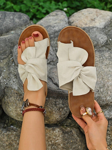 Women's flat slide sandals with bow tie, knot, and braided details, toe post design, and bohemian plant pattern.