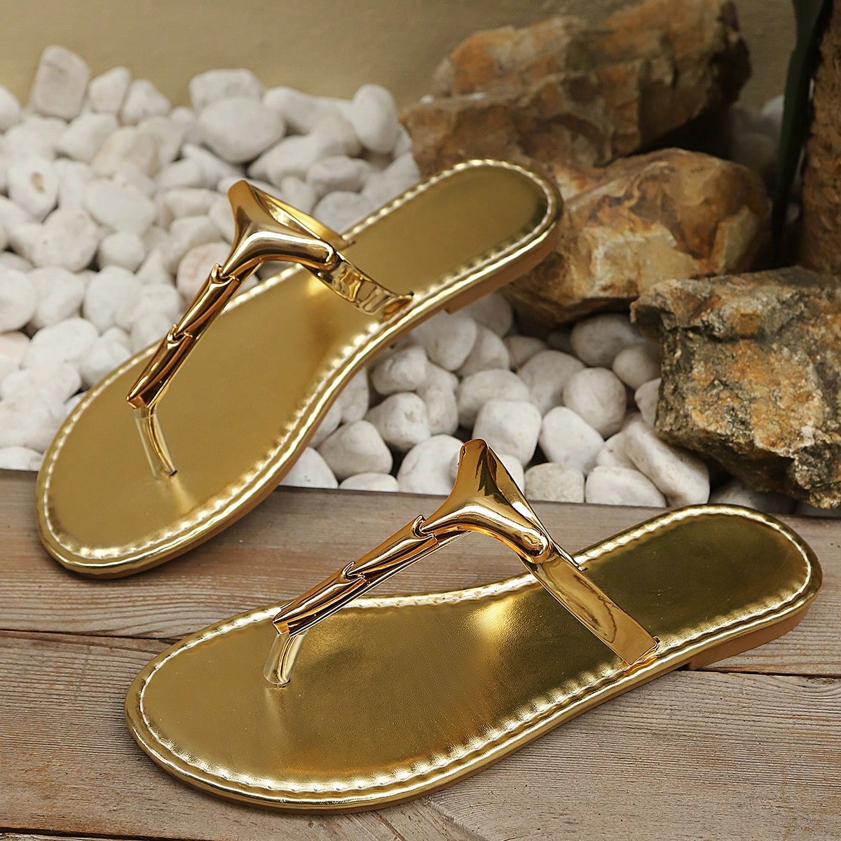 Women’s gold flat slide sandals with open toe post design and metal buckle detail, shown as fashionable outdoor summer footwear.