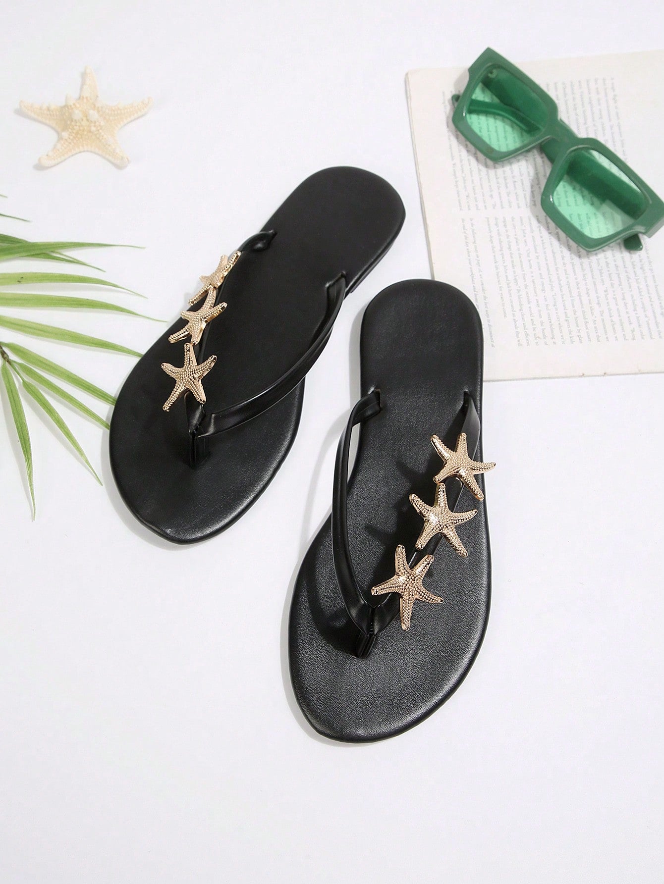 Women's black strappy flip flops with geometric pattern and star detail, flat heel, slip-on style, suitable for beach, indoor, and outdoor walking.