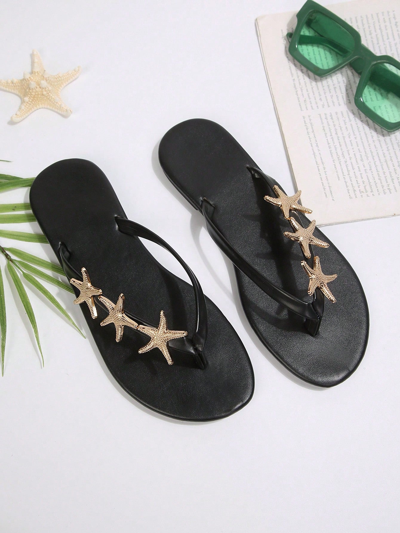 Women's black strappy flip flops with geometric pattern and star detail, flat heel, slip-on style, suitable for beach, indoor, and outdoor walking.
