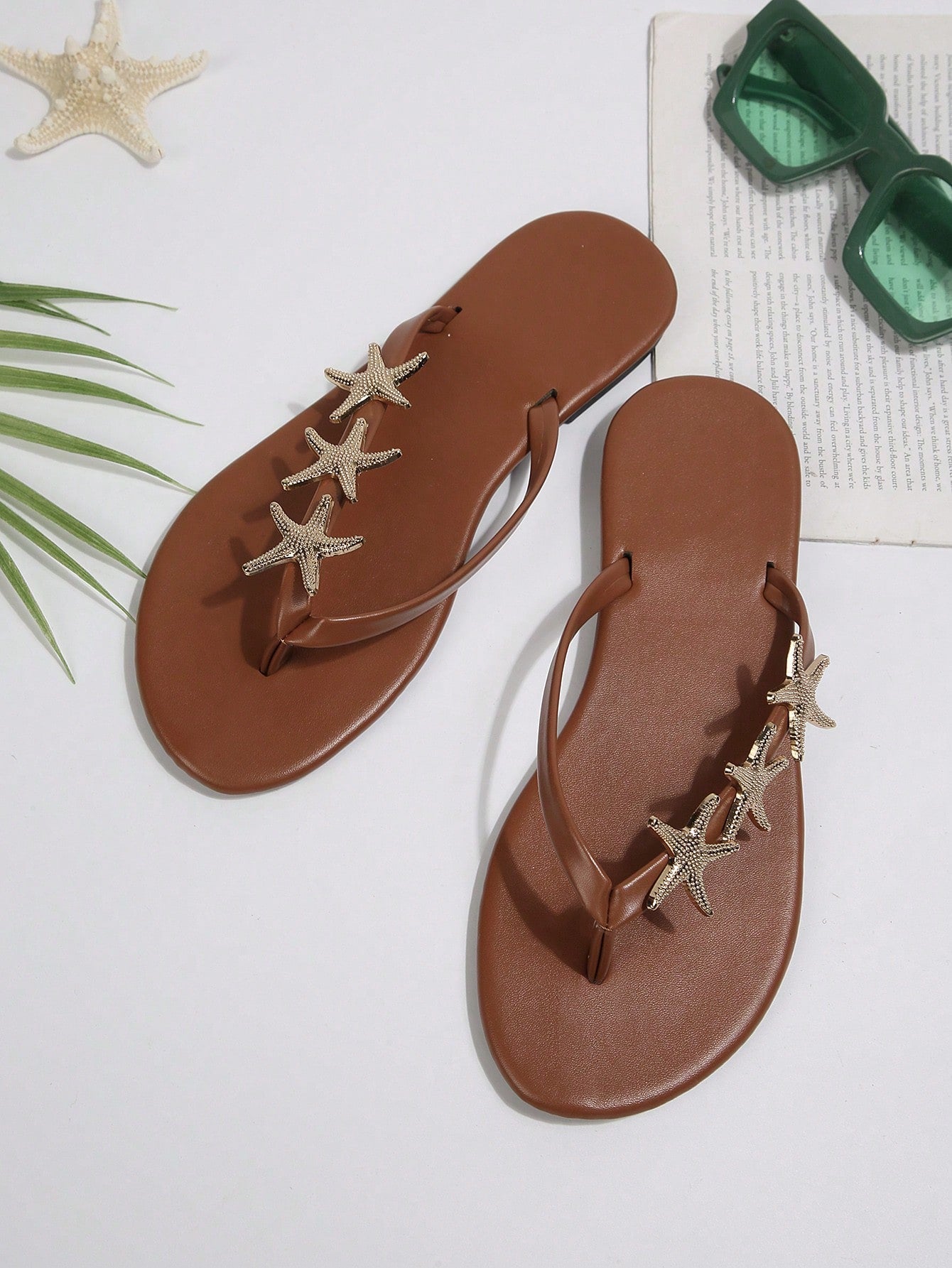 Women's black strappy flip flops with geometric pattern and star detail, flat heel, slip-on style, suitable for beach, indoor, and outdoor walking.
