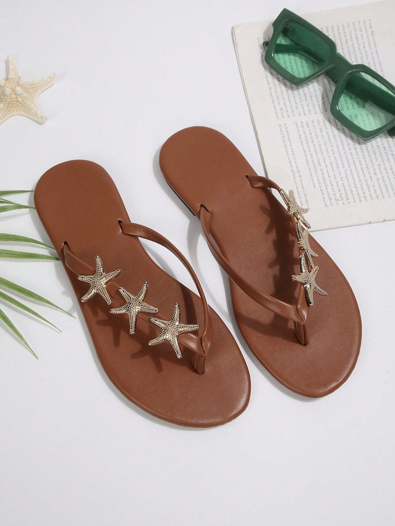 Women's black strappy flip flops with geometric pattern and star detail, flat heel, slip-on style, suitable for beach, indoor, and outdoor walking.