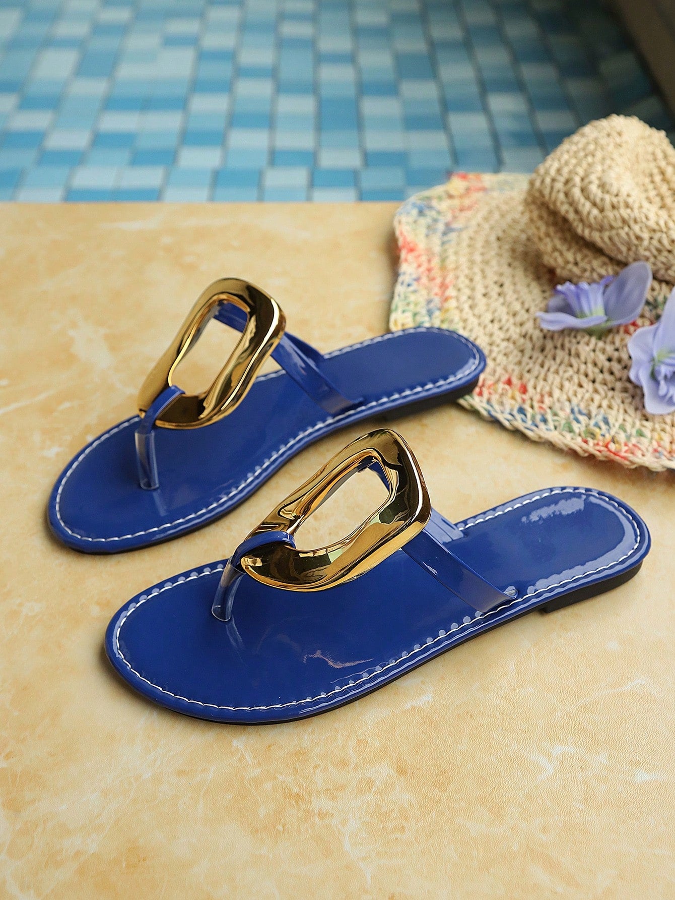 Women’s gold flat slide sandals with open toe post design and metal buckle detail, shown as fashionable outdoor summer footwear.