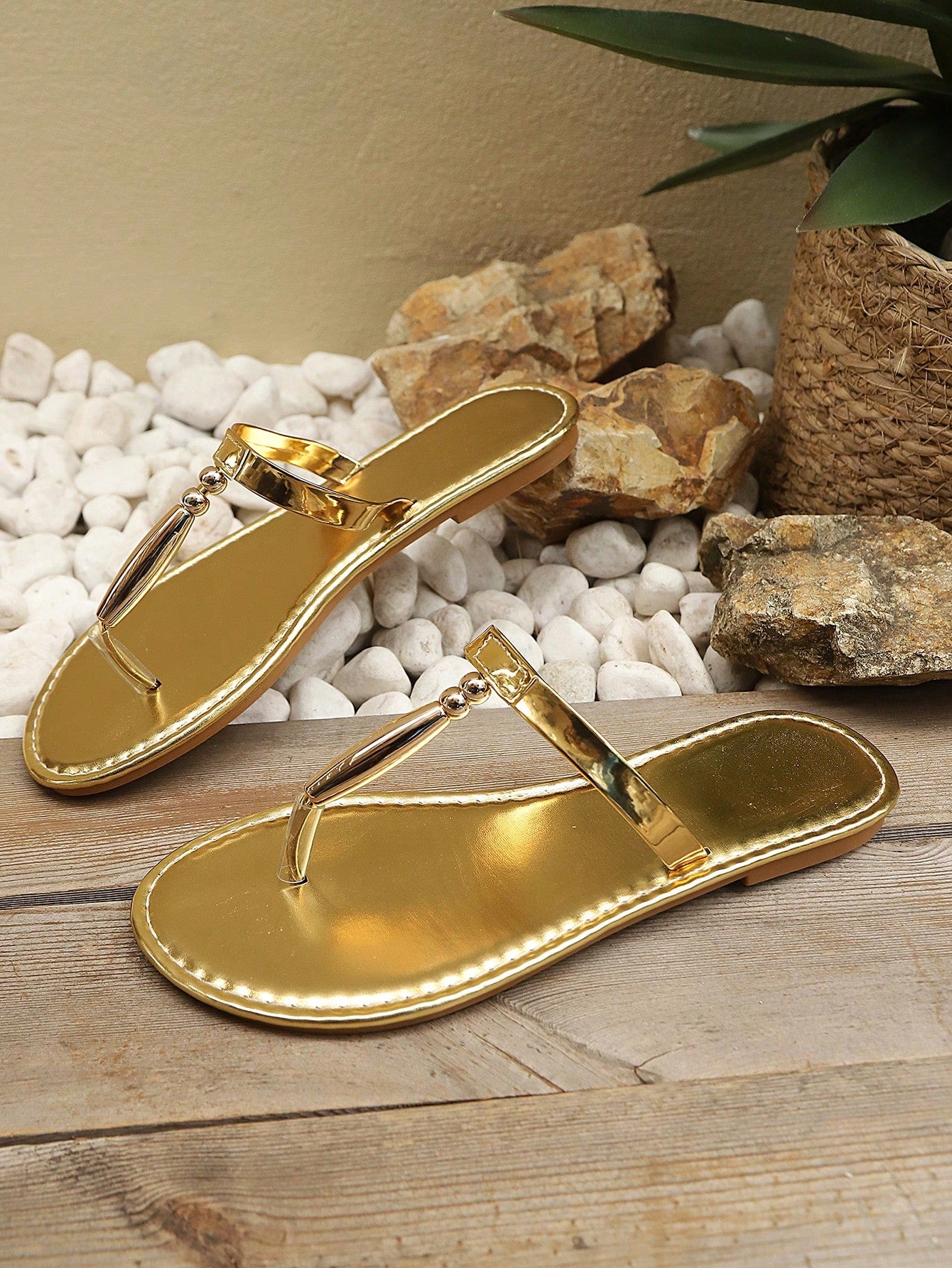 Women’s gold flat slide sandals with open toe post design and metal buckle detail, shown as fashionable outdoor summer footwear.