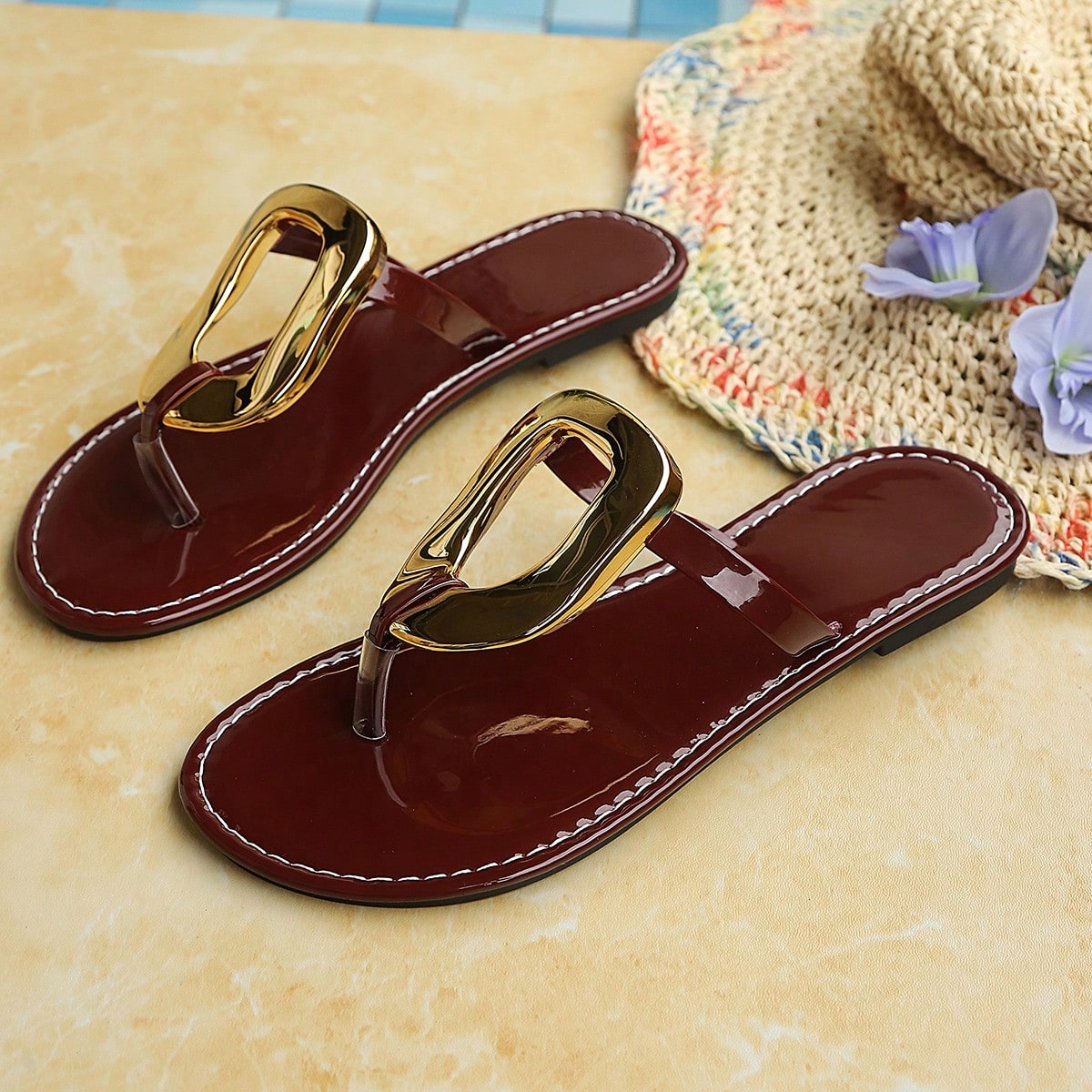 Women’s gold flat slide sandals with open toe post design and metal buckle detail, shown as fashionable outdoor summer footwear.