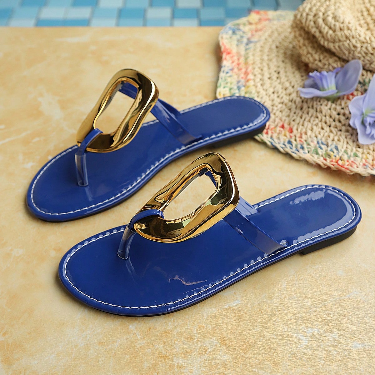 Women’s gold flat slide sandals with open toe post design and metal buckle detail, shown as fashionable outdoor summer footwear.
