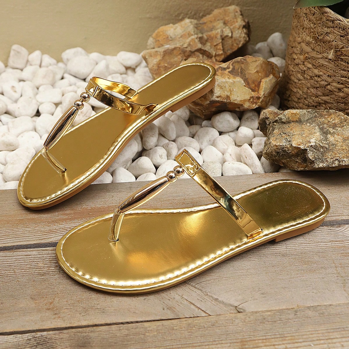 Women’s gold flat slide sandals with open toe post design and metal buckle detail, shown as fashionable outdoor summer footwear.
