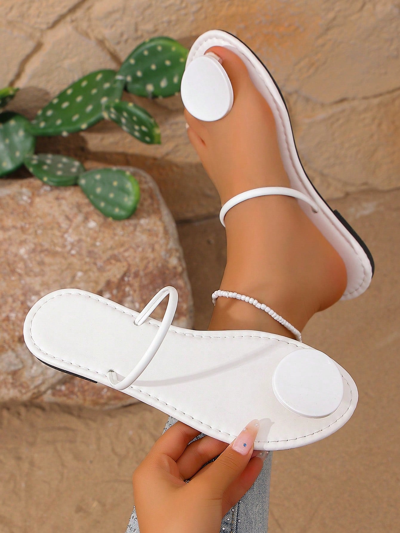 Women’s flat thong sandals with a shiny round buckle, high-gloss finish, semi-circle strap, and toe post design