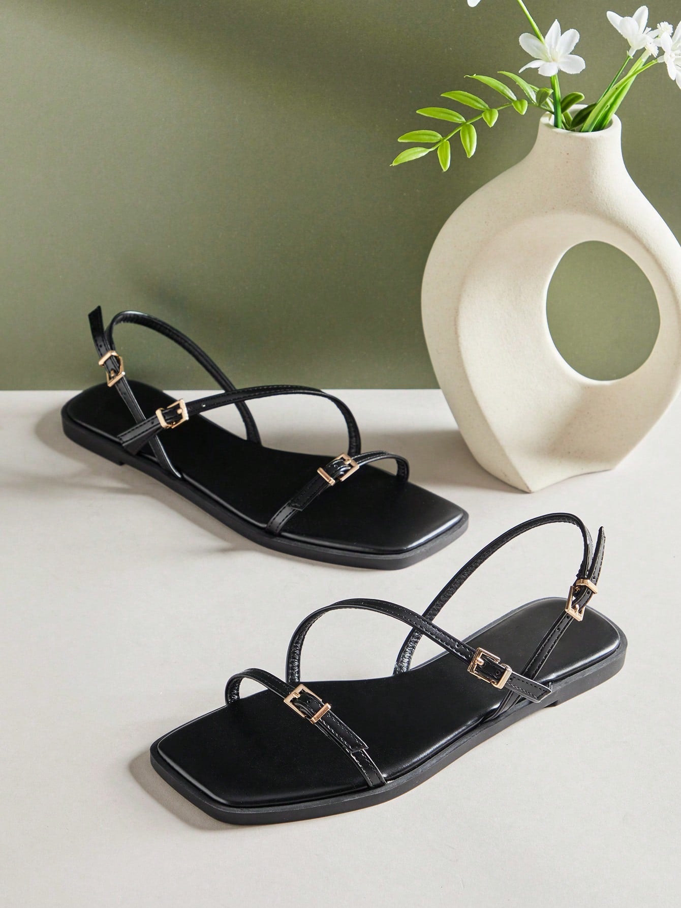 Women's flat open-toe sandals featuring a buckle detail and PU leather construction with a flat sole.