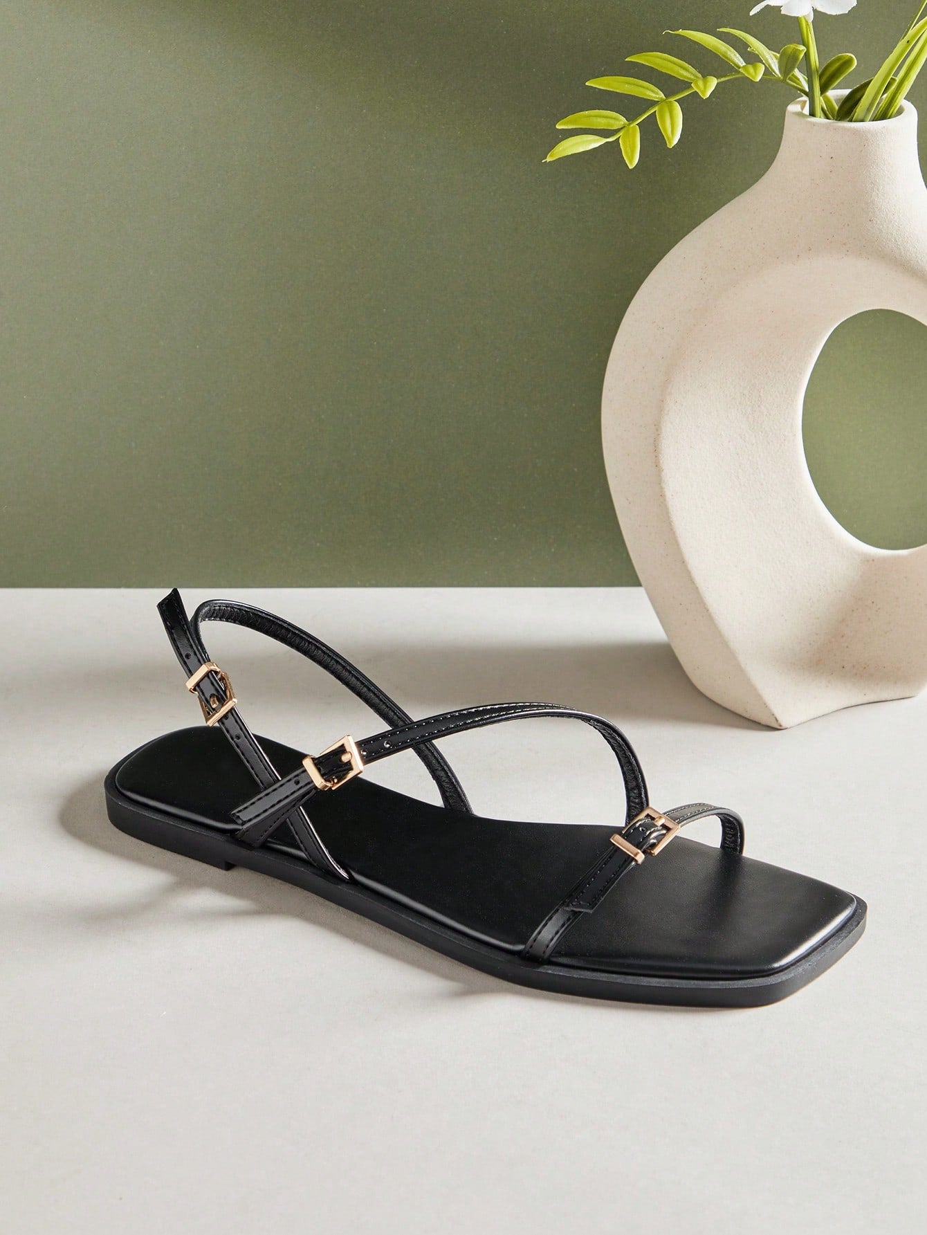 Women's flat open-toe sandals featuring a buckle detail and PU leather construction with a flat sole.