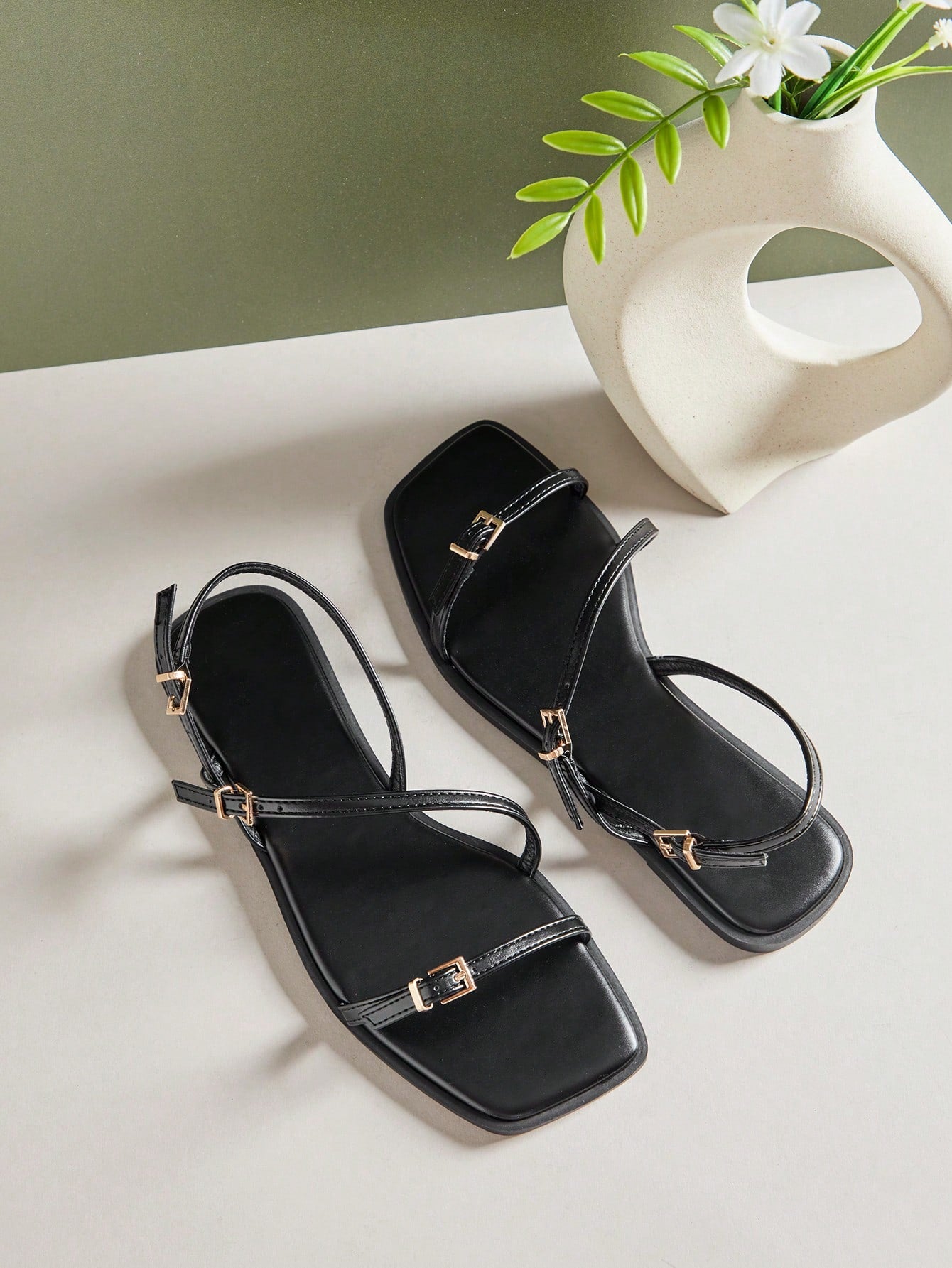 Women's flat open-toe sandals featuring a buckle detail and PU leather construction with a flat sole.
